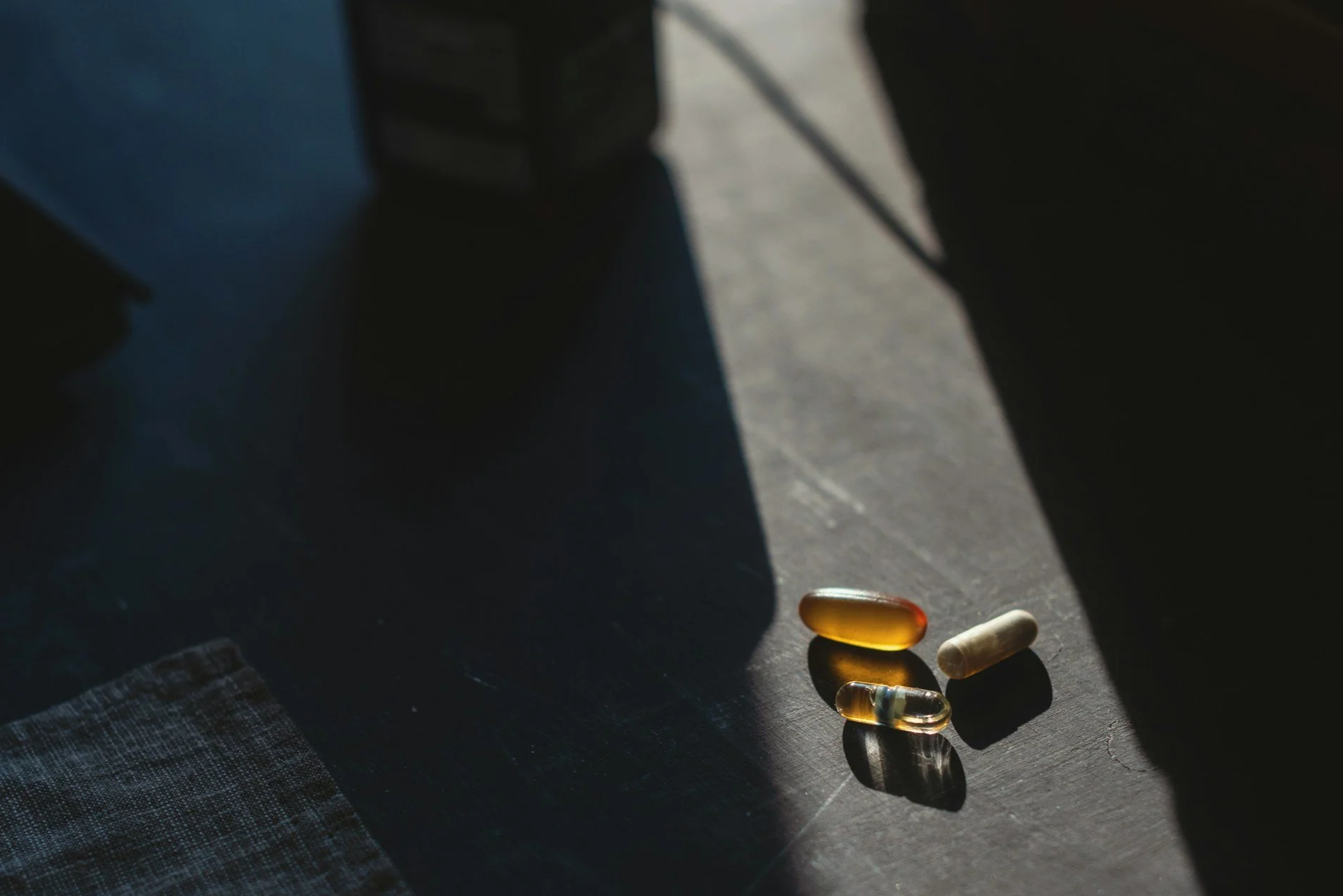 Various supplements on a dark surface with shadows cast over them.