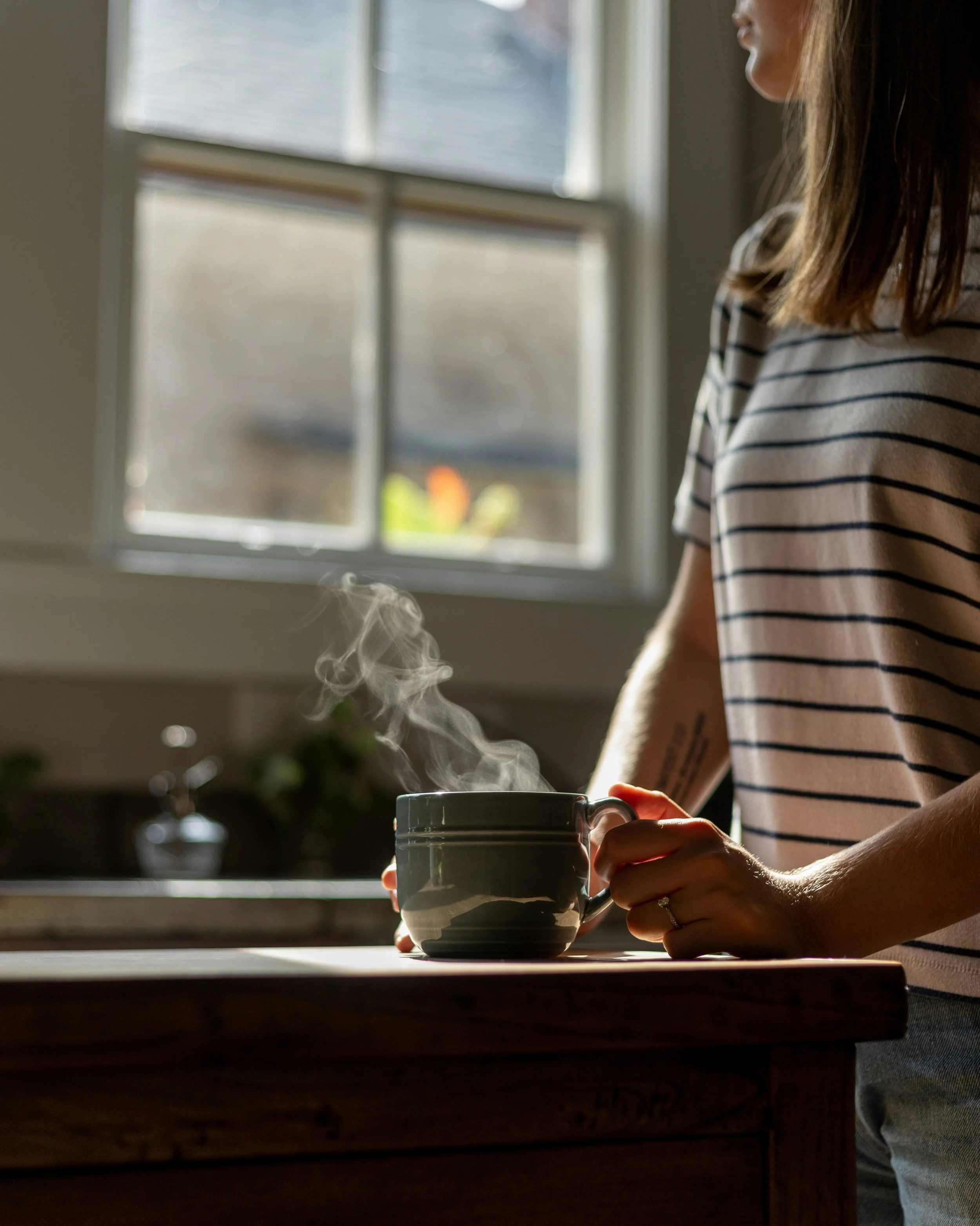 Woman preparing tea at a kitchen counter symbolizing daily living support and comforting home routines.