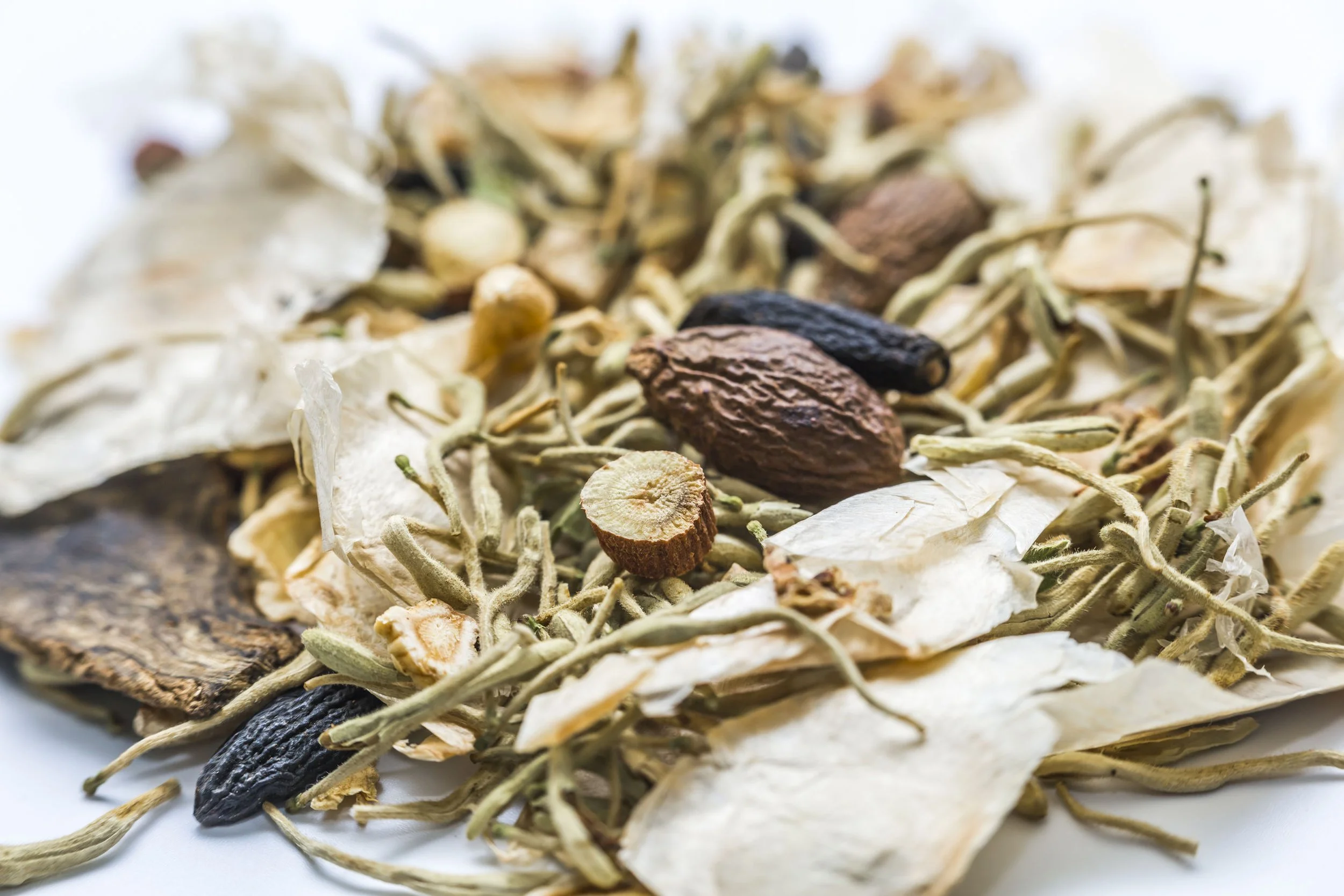 Close-up of dried herbs, spices, and plant materials including honeysuckle, gardenia dried leaves, and pods.