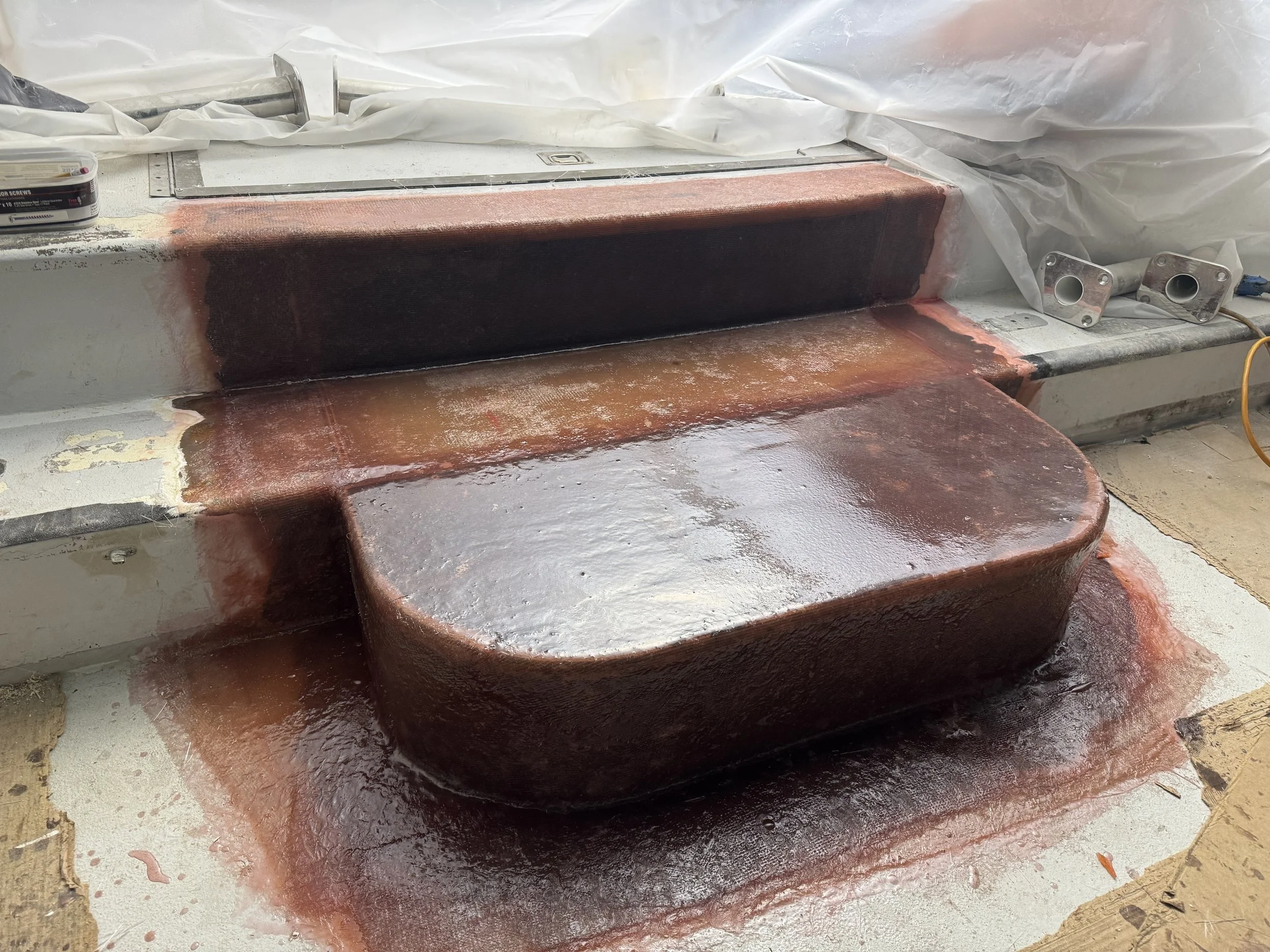 A copper heat sink or component being freshly refined or assembled, with visible solder or flux residue around it, on a workbench with tools and materials in the background.