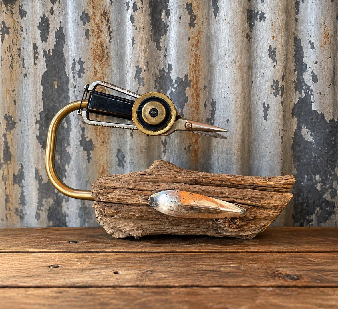 Vintage hand-crank tool mounted on driftwood with a metal spoon, displayed against a distressed corrugated metal backdrop