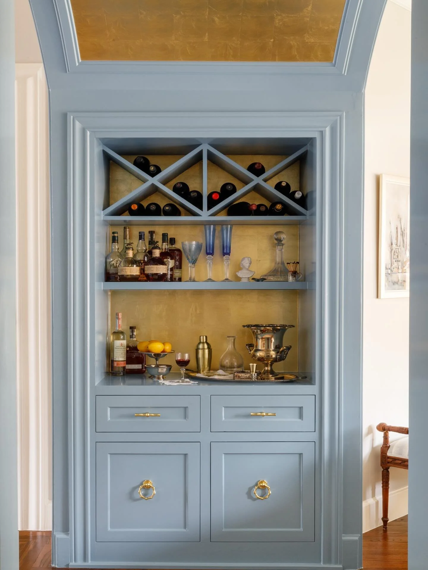 This hidden bar nook balances tailored sophistication with a hint of whimsy &mdash; Marlboro Blue cabinetry, brass accents, and a luminous metallic backdrop that turns every cocktail into a small celebration. 
📸: @rachelalysemanning 

#InteriorDesig