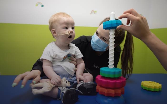 Premature infant therapy session in Houston helping a baby build motor skills with colorful stackable rings.