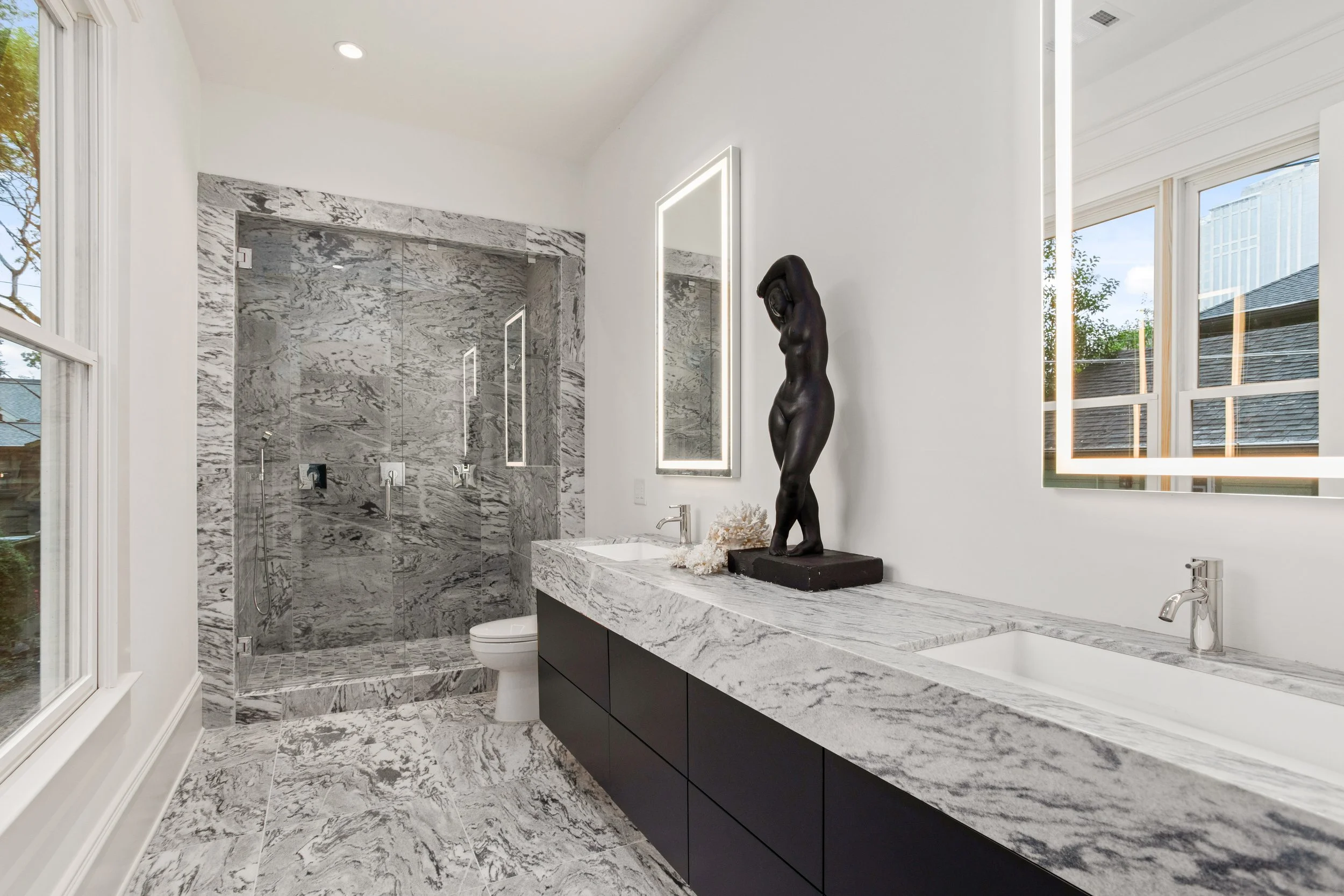 Designed as a private retreat, the primary bathroom showcases a double vanity crowned with an ultra-thick slab of Georgia marble, paired with a spacious walk-in shower outfitted with six sprayers for an indulgent, spa-level experience.