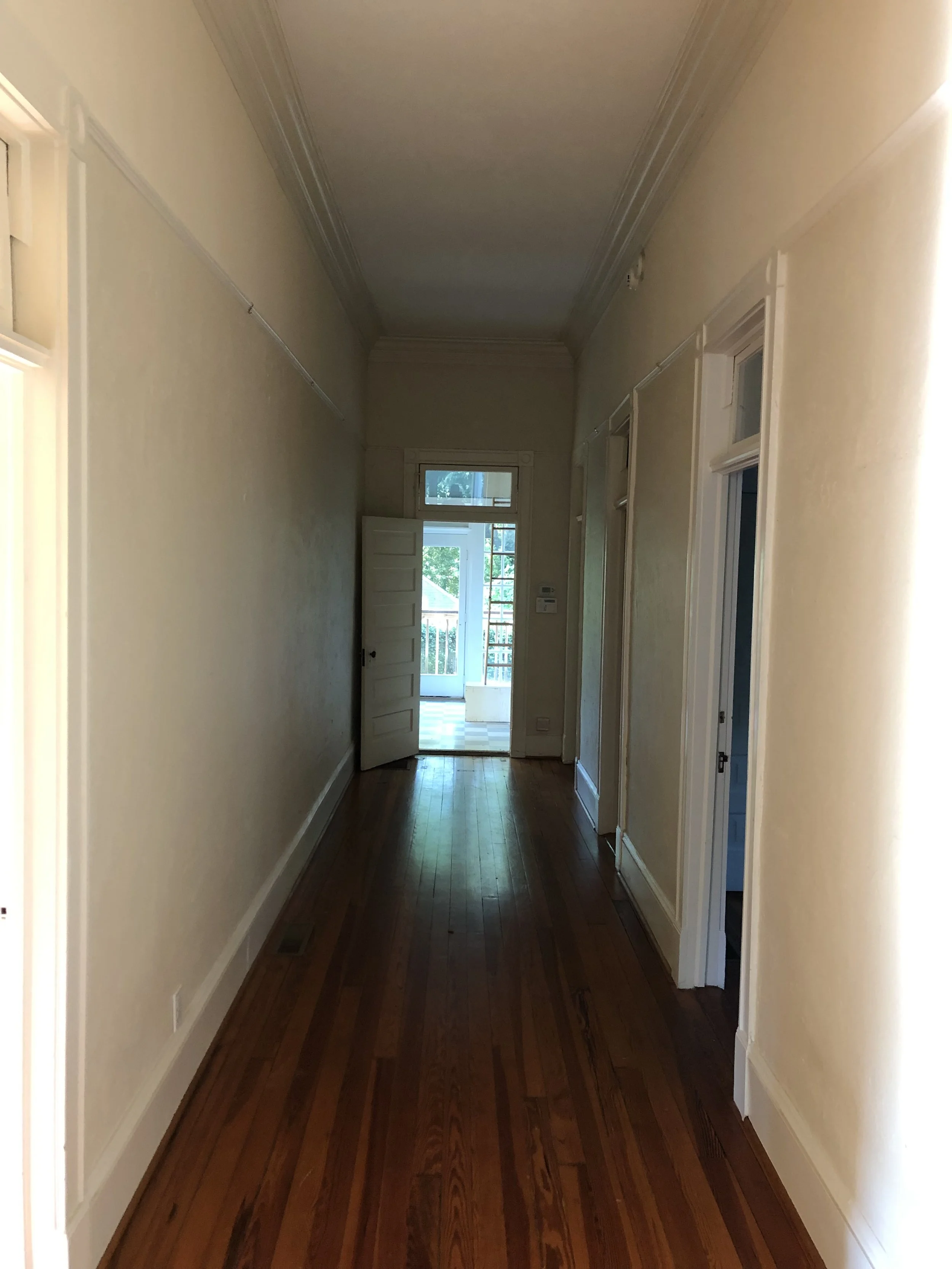 The "before" version of the home's main hallway - dark, closed in, no lighting at all