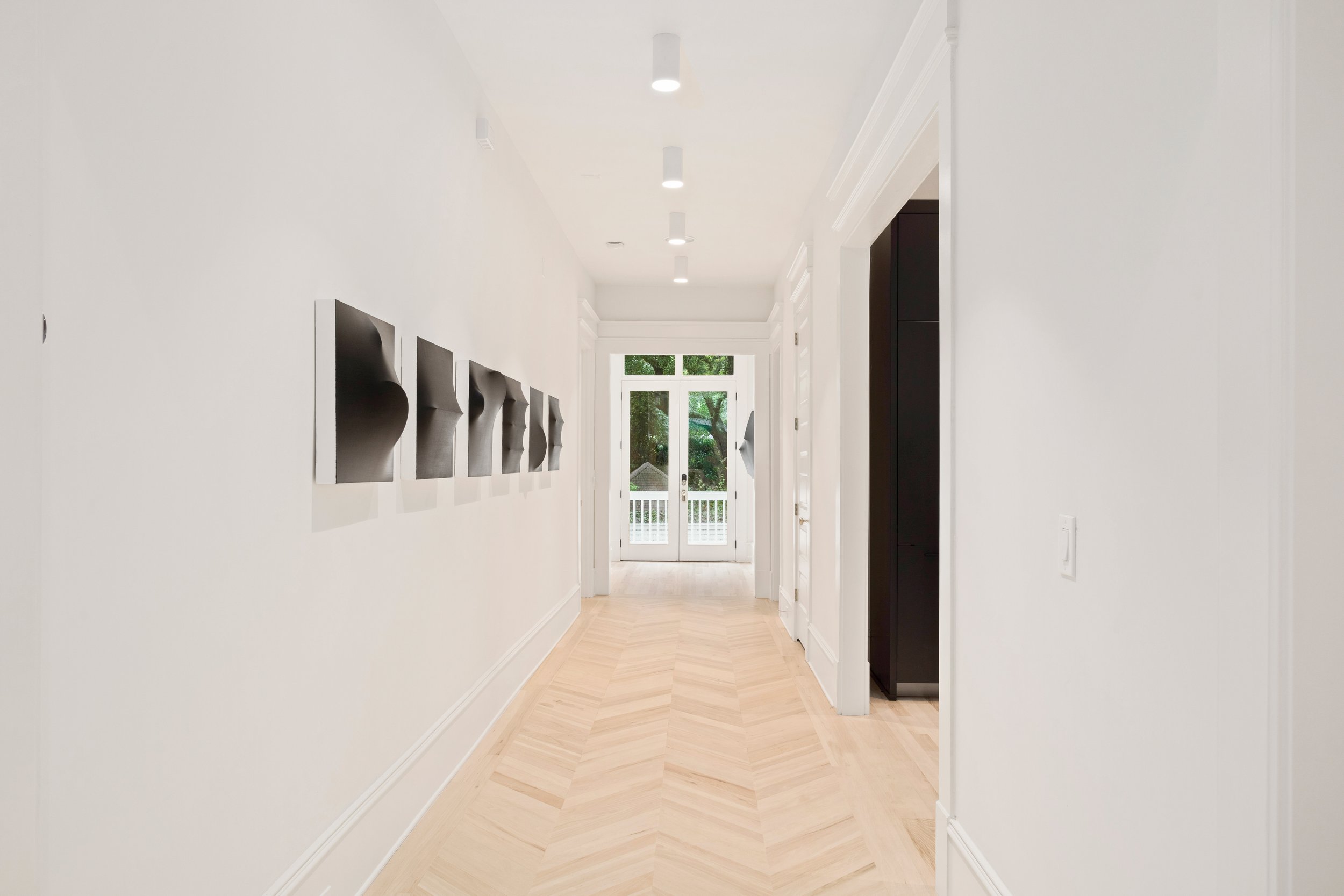 Serving as the main artery of the home, this grand hallway offers uninterrupted views from the front door to the backyard and was designed to make a striking first impression. A new, larger double door with floor-to-ceiling glass, paired with herring