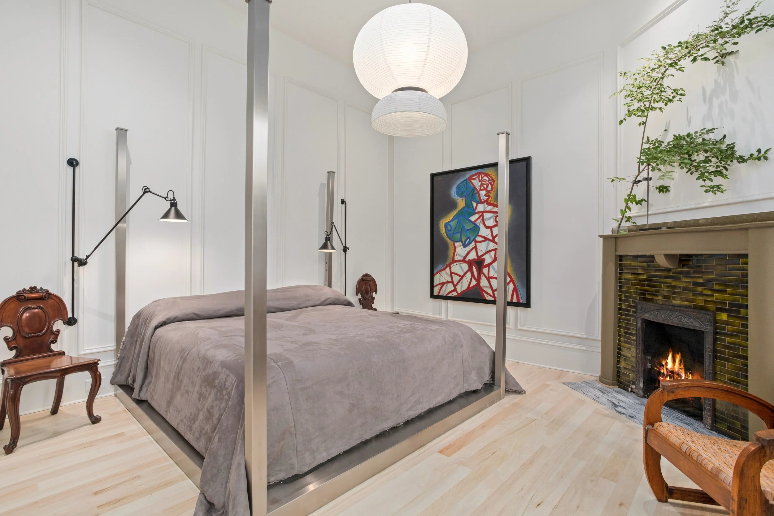 The primary bedroom is anchored by an original, working fireplace and offers ample space for a king-sized bed, with picture-frame wall molding lending an elevated, classic feel.