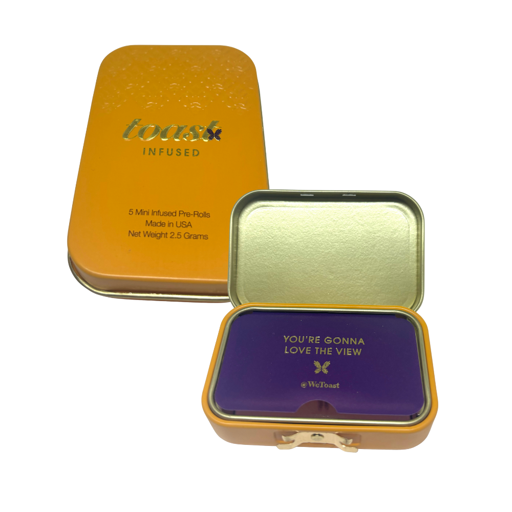 A metal tin with a purple lid that says 'You're Gonna Love The View @WeToast' in gold letters, and an orange metal container labeled 'toast infused' with five mini infused pre-rolls inside.