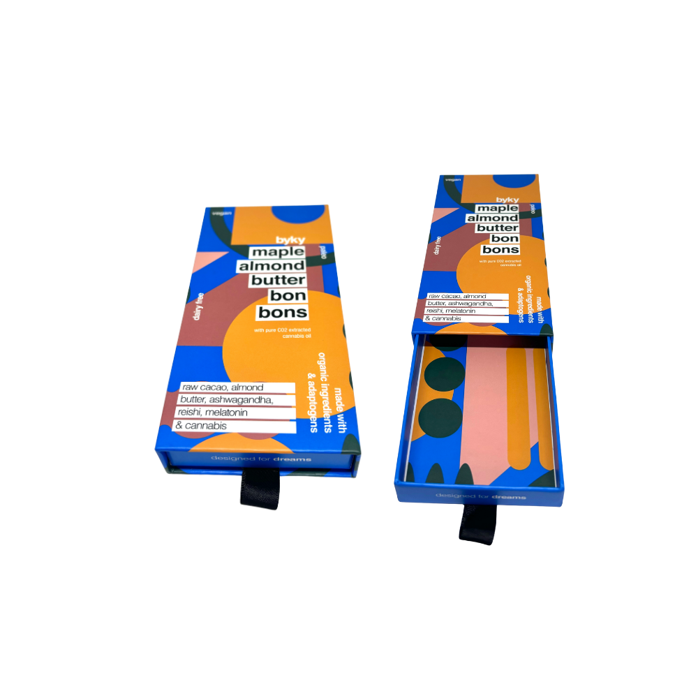 A box labeled 'Heavy Metal Single Blunt 0.75g' positioned next to an open rectangular container with artwork inside featuring a dark, moody scene with a figure.