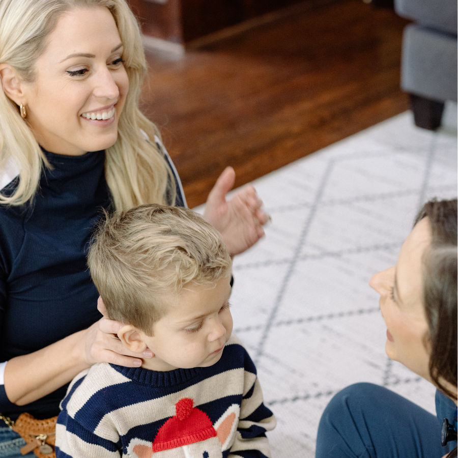 A woman with blonde hair smiling and talking to a pediatric doctor with dark hair and a boy, talking about pediatric services for child.