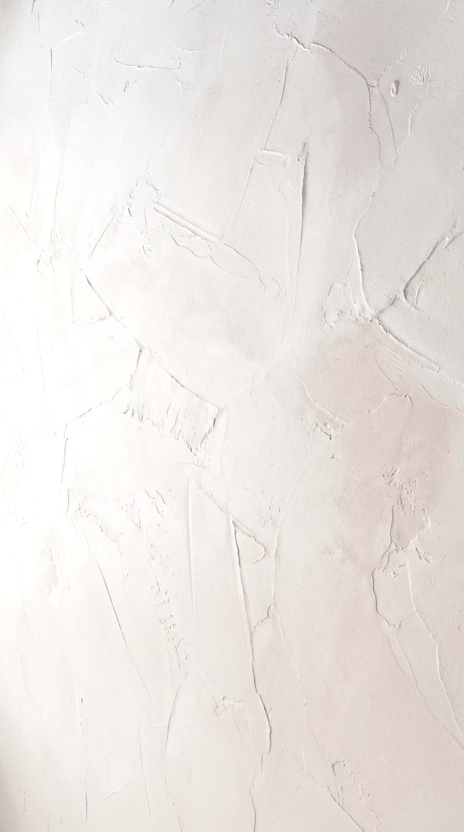 Close-up of a white lime plaster wall showing natural texture, depth, and subtle surface movement.