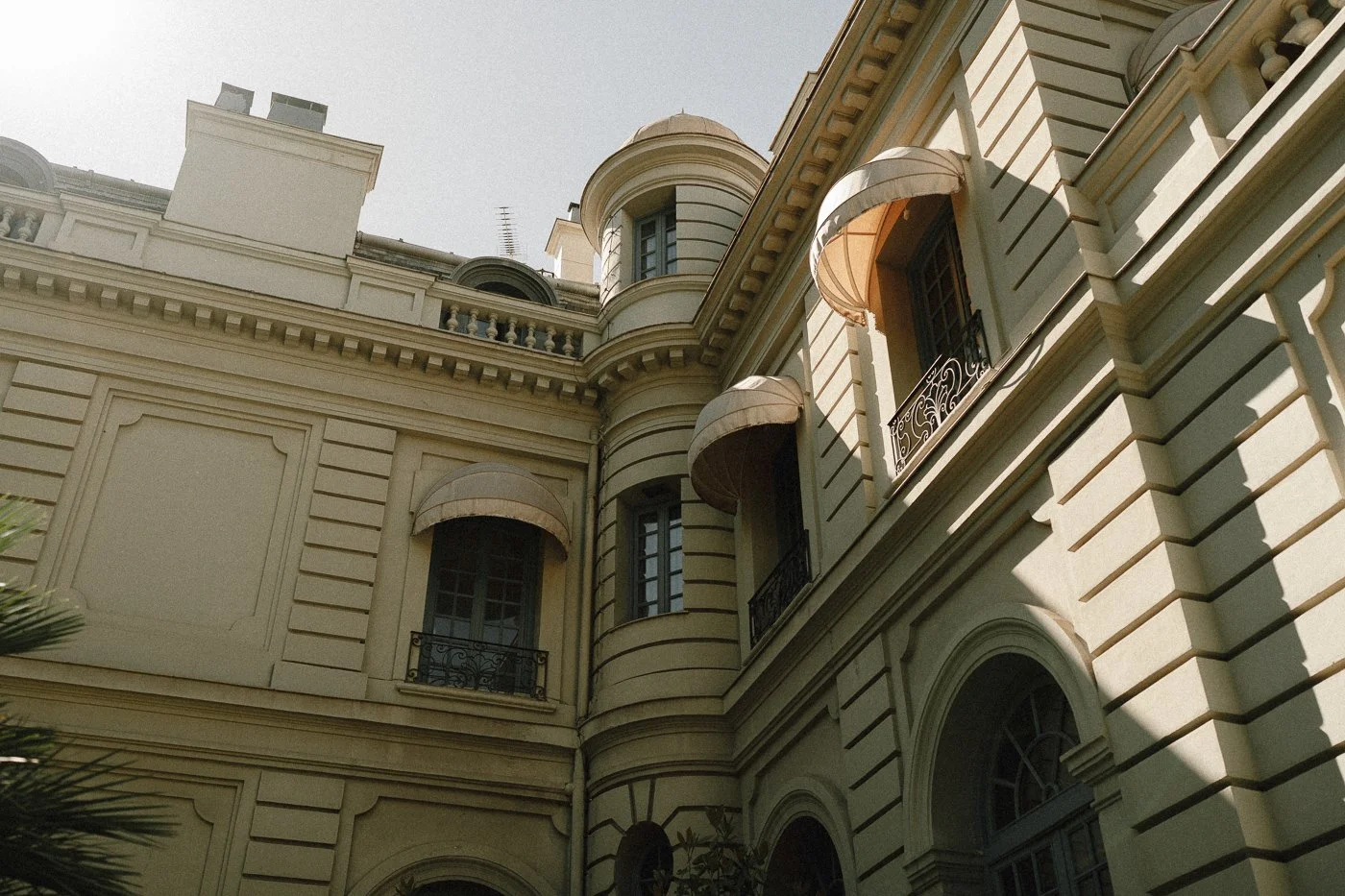 Vista de un edificio antiguo de estilo europeo con fachadas de color claro, ventanas con rejas y balcones con barandillas de hierro
