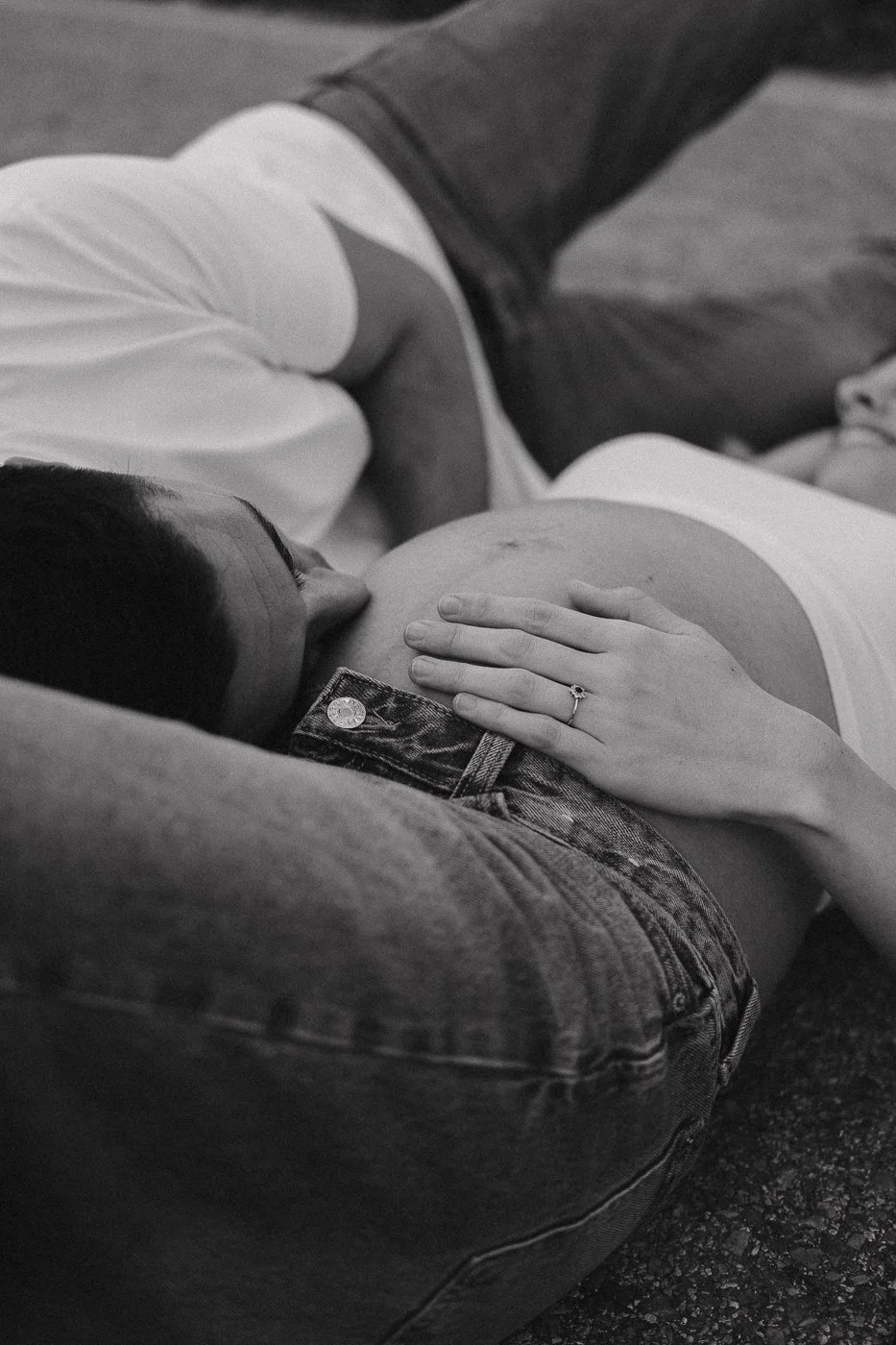 Una pareja en un momento íntimo, con uno de ellos usando un anillo en la mano, en un entorno en tonos grises.