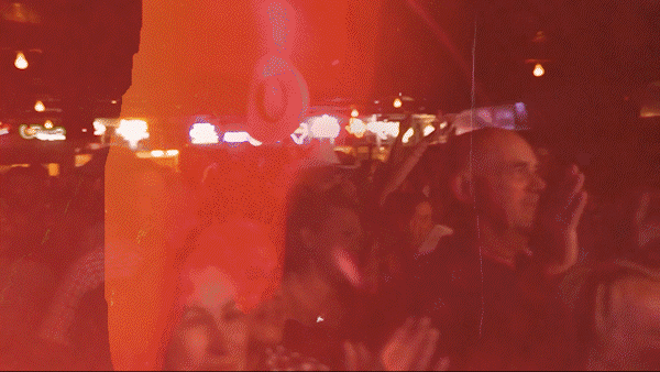 People at a nighttime event or party, illuminated by red and orange lighting, smiling and enjoying themselves.