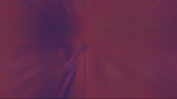 Close-up of a pin in the center of colorful, blurred light streaks creating a radial pattern.