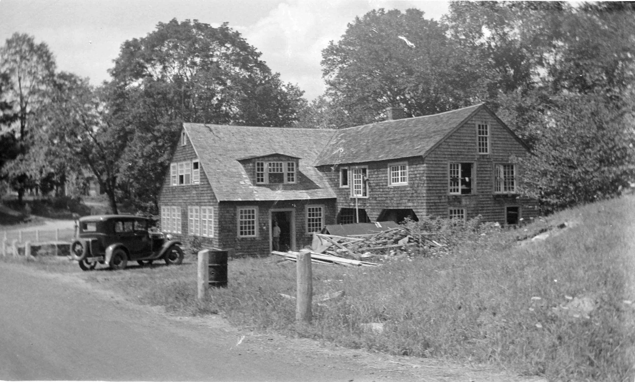 A black and white historic photo of Chase's Mill with an early automobile out front