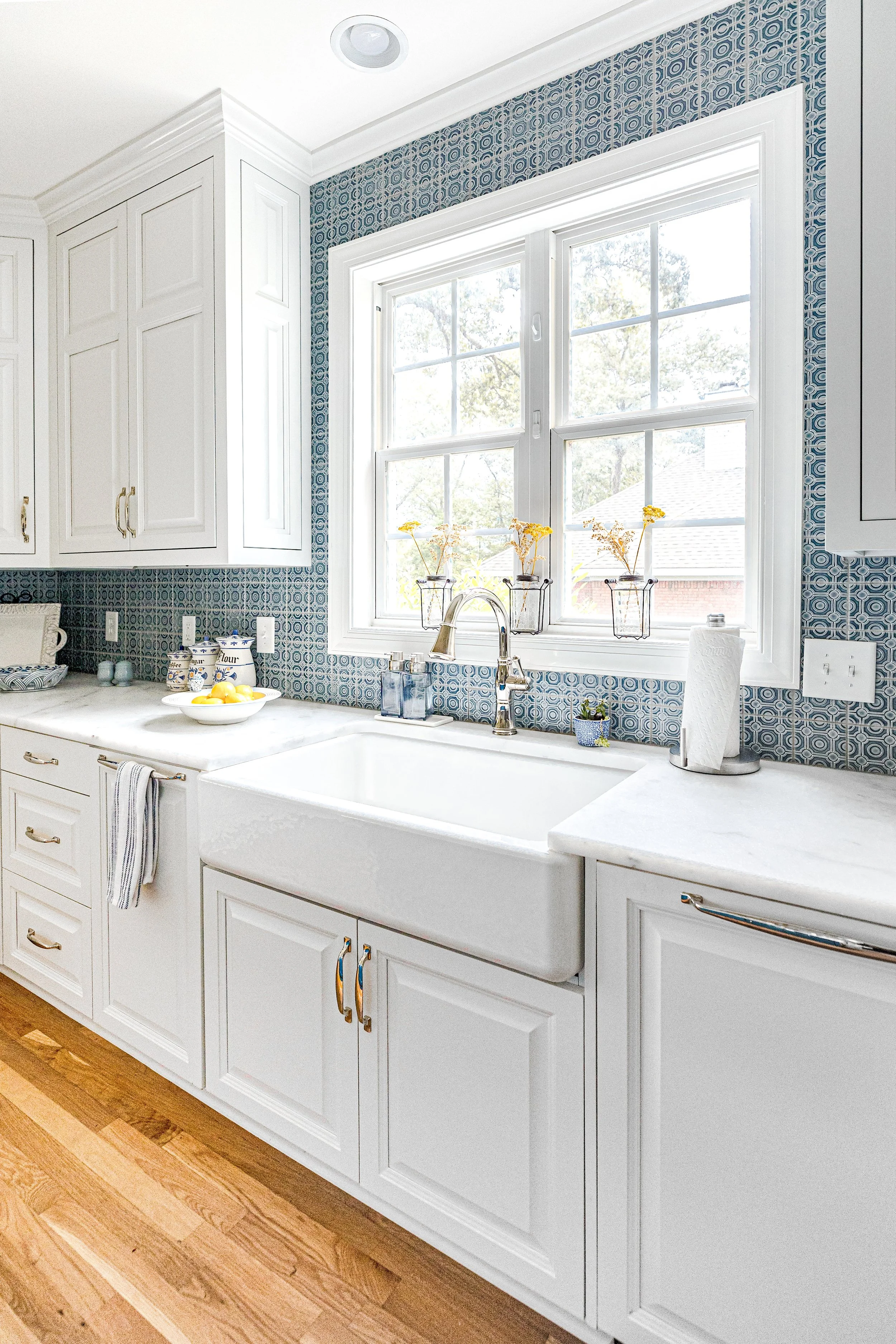 A bright, functional, and stylish kitchen designed by Cossart Design, featuring crisp white cabinetry, custom backsplash, and playful blue accents. Thoughtfully selected finishes and layout make this kitchen ideal for cooking, entertaining, and daily