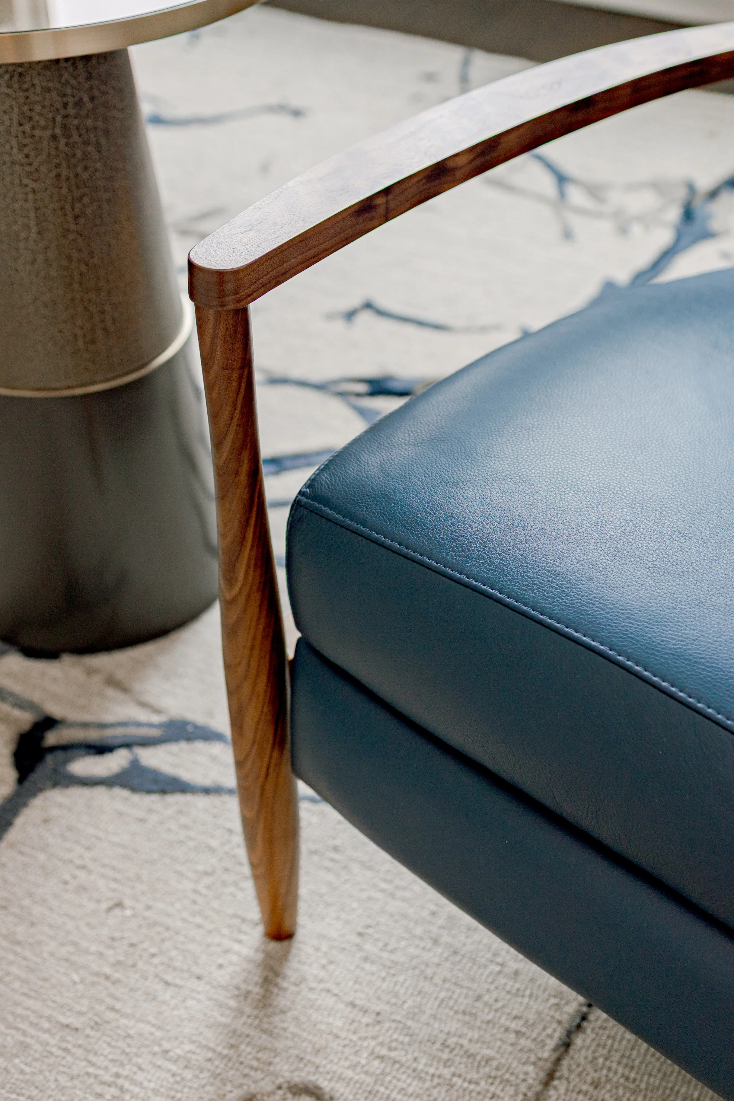 An intimate sitting area designed with comfort and intention underneath a cascading, floating staircase, offering a cozy retreat within the home. Carefully selected seating, layered textiles, and warm tones create a space ideal for quiet moments or r