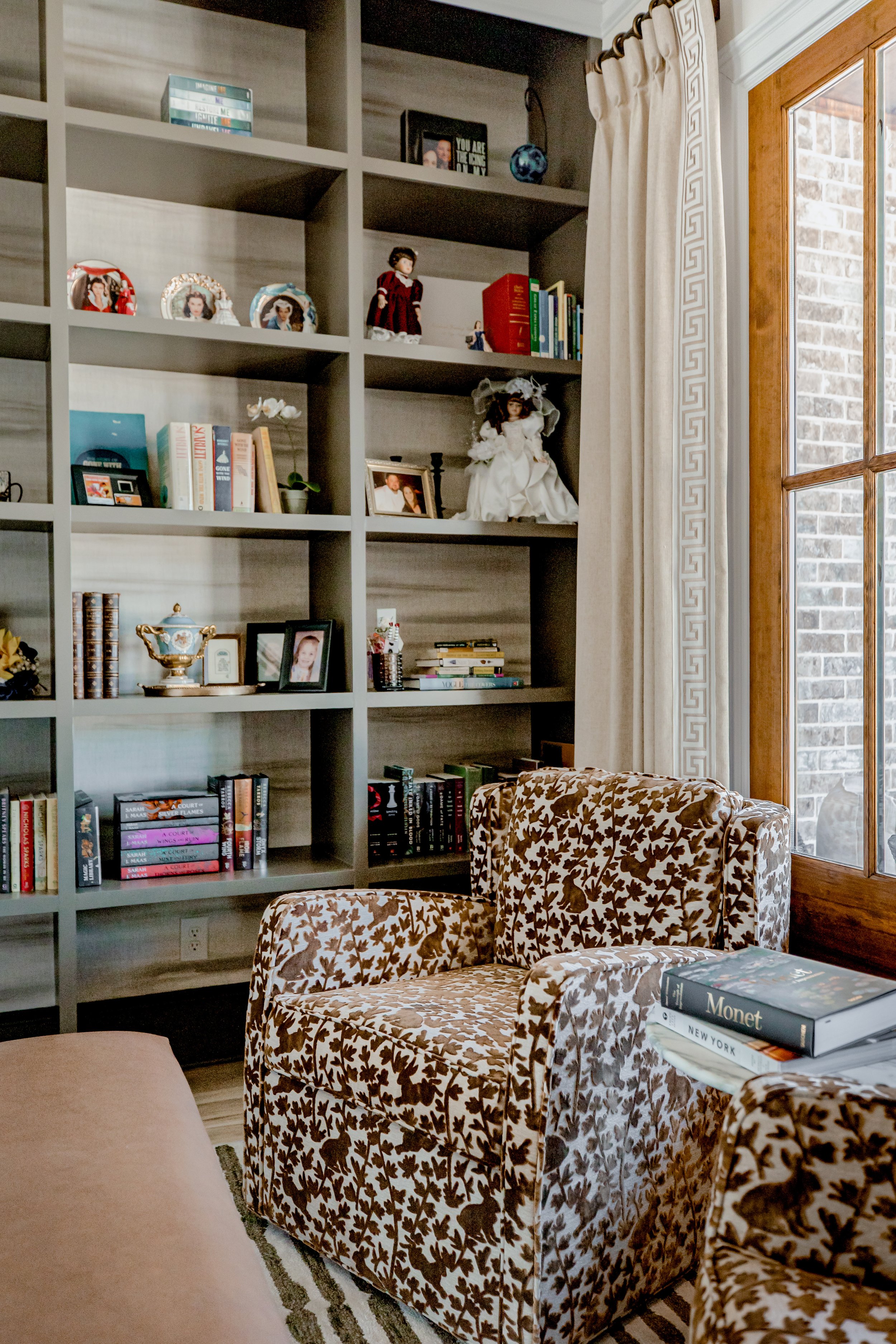 An elegant library space by Cossart Design that reflects the home’s Southern heritage through rich wood tones, tailored built‑ins, and curated book collections. Custom shelving, plush seating, and layered lighting create a sophisticated yet cozy envi