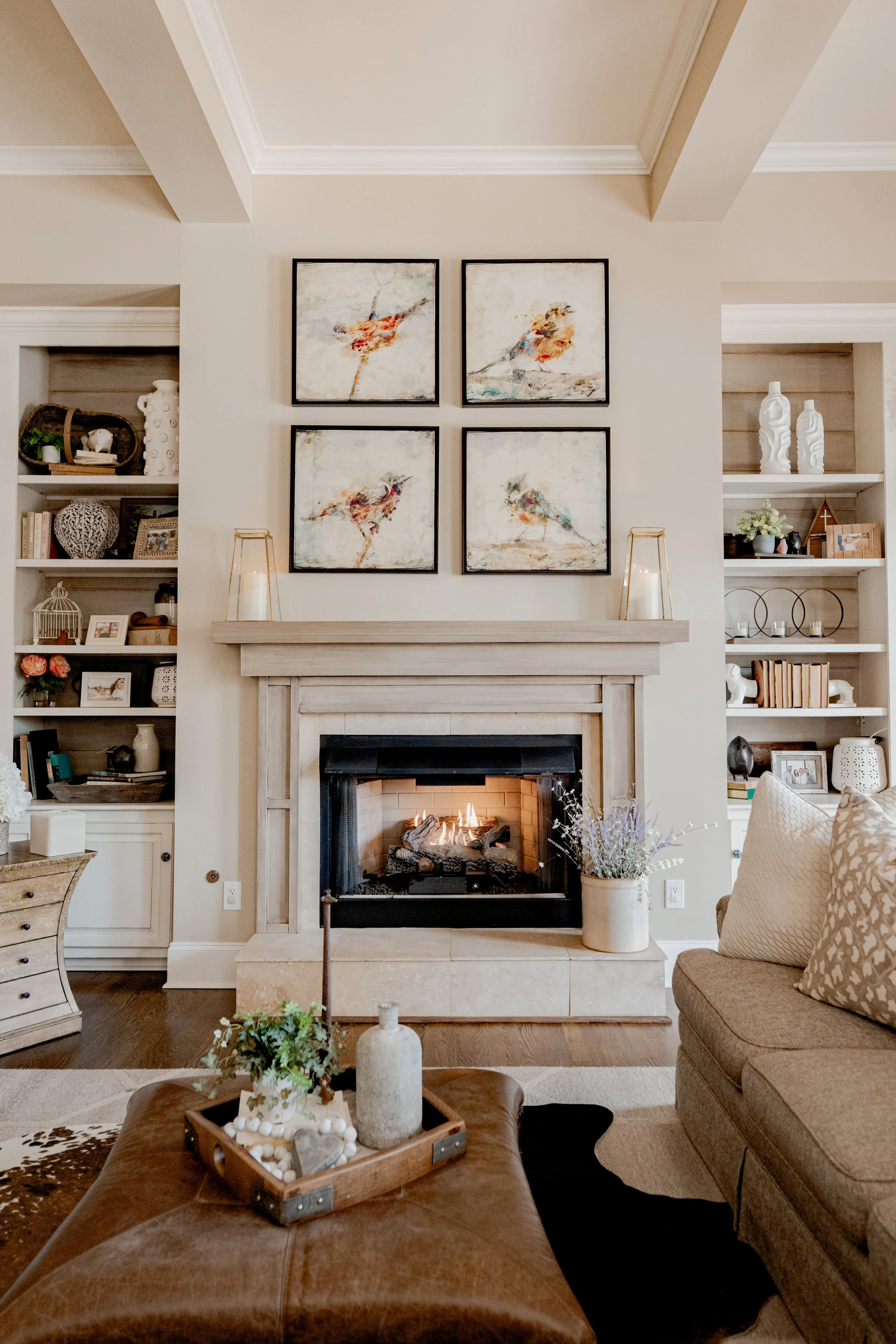 A warm and inviting living room/den by Cossart Design, featuring a cozy fireplace, built-in bookcases, and rich textures throughout. The design blends comfort and luxury, with layered furnishings, custom accents, and thoughtful layout that make the s