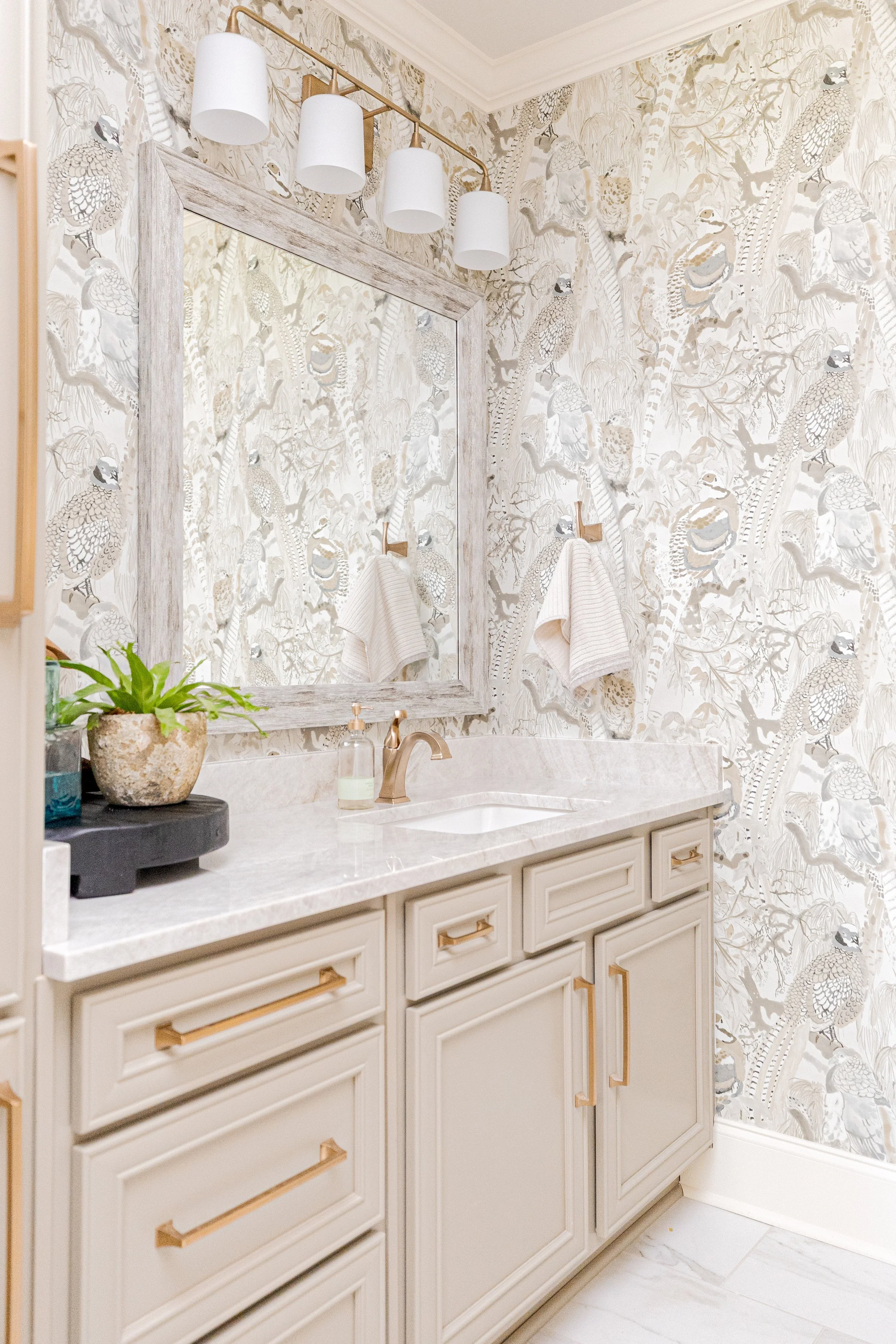 A spa-inspired primary bathroom designed for relaxation and daily ritual. Elevated materials, balanced lighting, and thoughtful layouts create a space that feels calming, timeless, and refined. The textured wallpaper custom tile, and gold finishes br