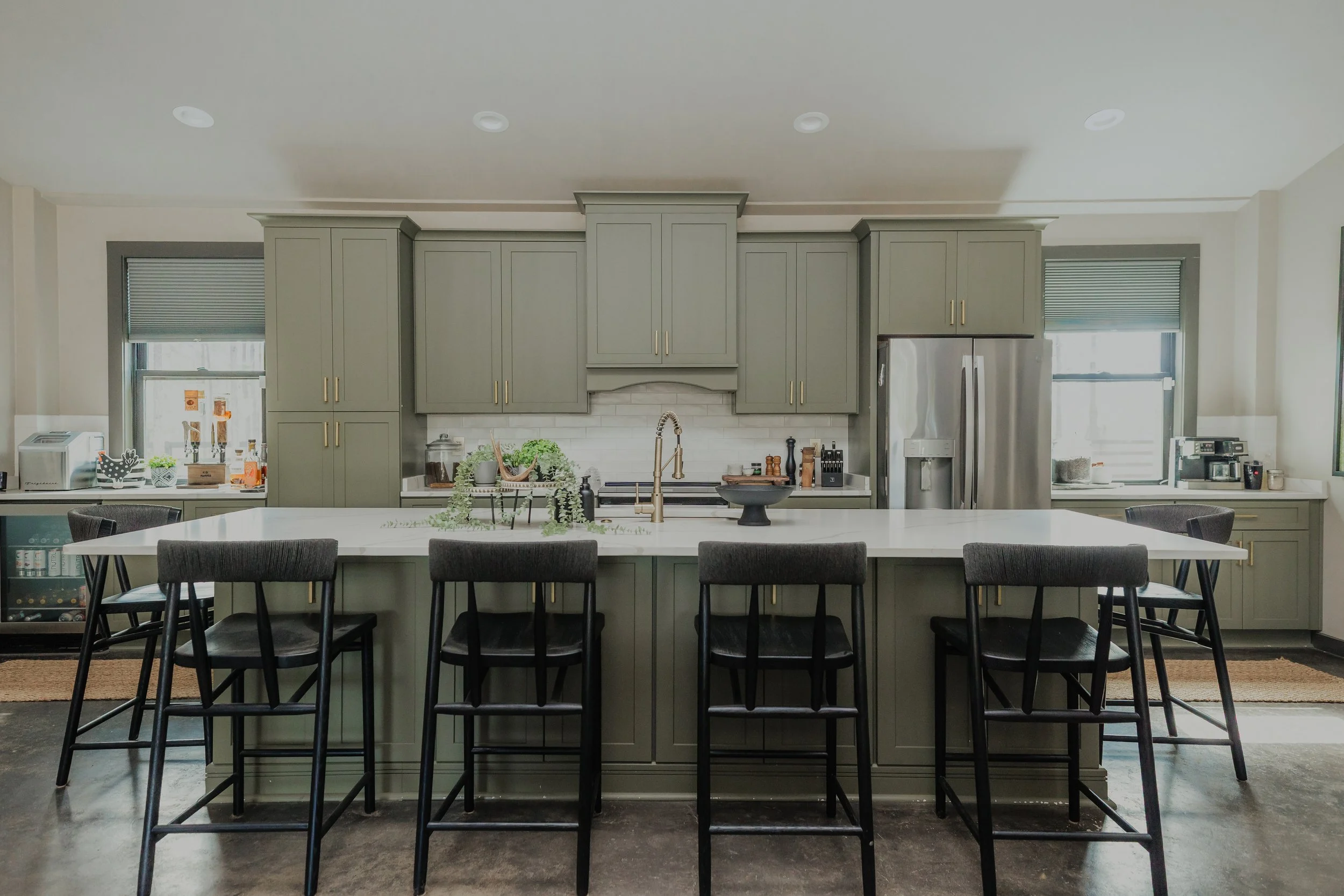 An open kitchen by Cossart Design that combines rugged sensibility with refined finishes, featuring stunning countertops and a custom backsplash that elevate the space. Industrial accents pair with sleek surfaces and thoughtfully selected materials t