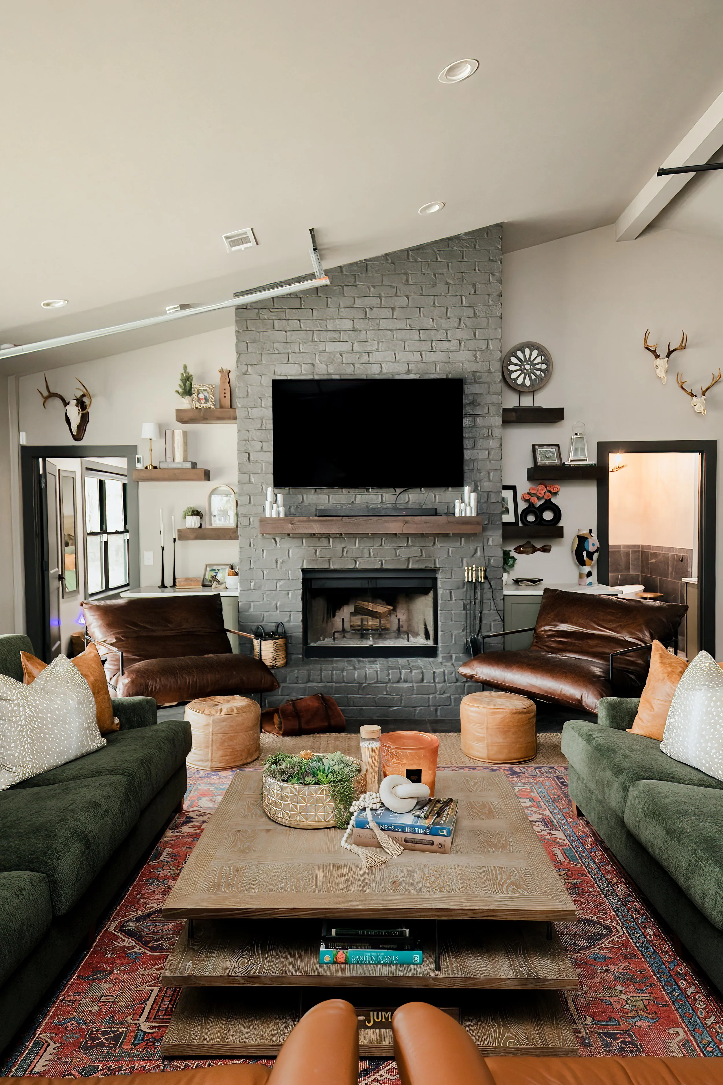 A striking open concept living space by Cossart Design in this Hawkinsville, GA barndominium that masterfully blends industrial accents with masculine design. Rich green and wood tones, along with modern tailored furnishings create a lodge‑inspired e