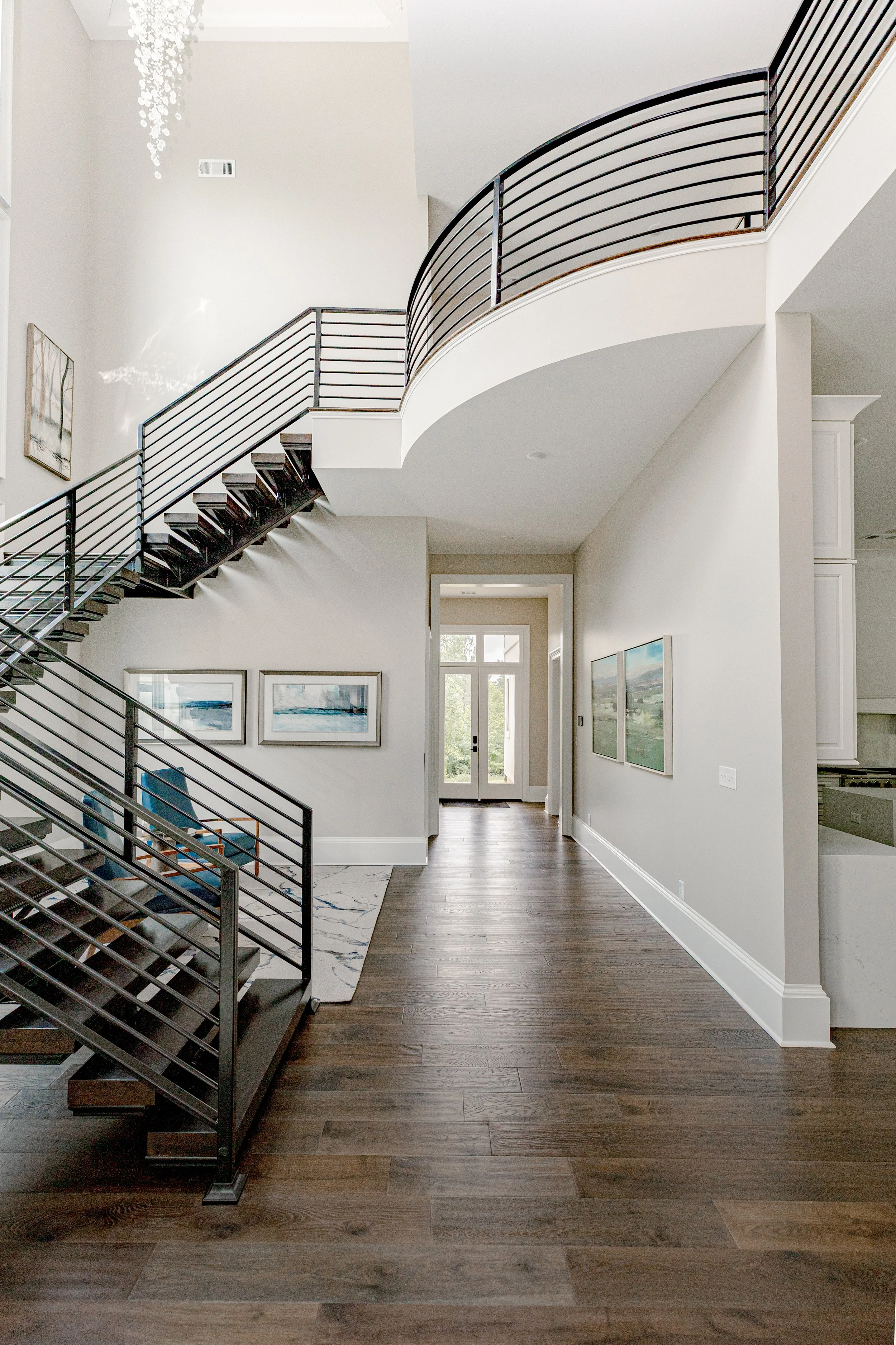 An intimate sitting area designed with comfort and intention underneath a cascading, floating staircase, offering a cozy retreat within the home. Carefully selected seating, layered textiles, and warm tones create a space ideal for quiet moments or r