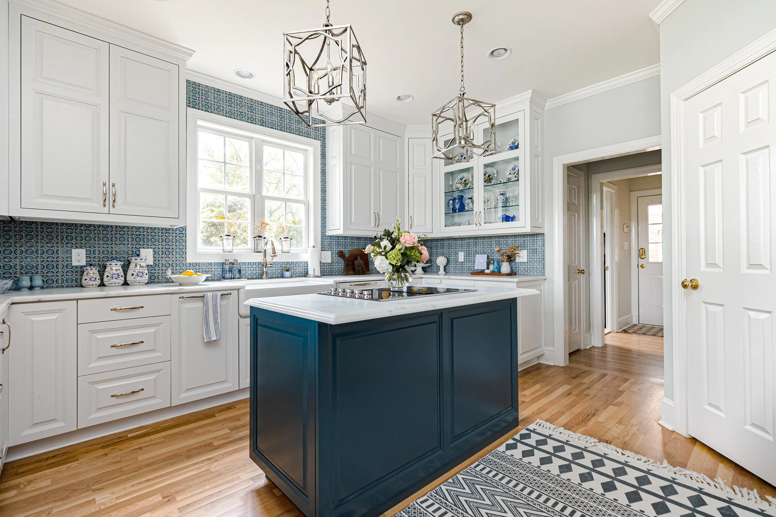 A bright, functional, and stylish kitchen designed by Cossart Design, featuring crisp white cabinetry, custom backsplash, and playful blue accents. Thoughtfully selected finishes and layout make this kitchen ideal for cooking, entertaining, and daily