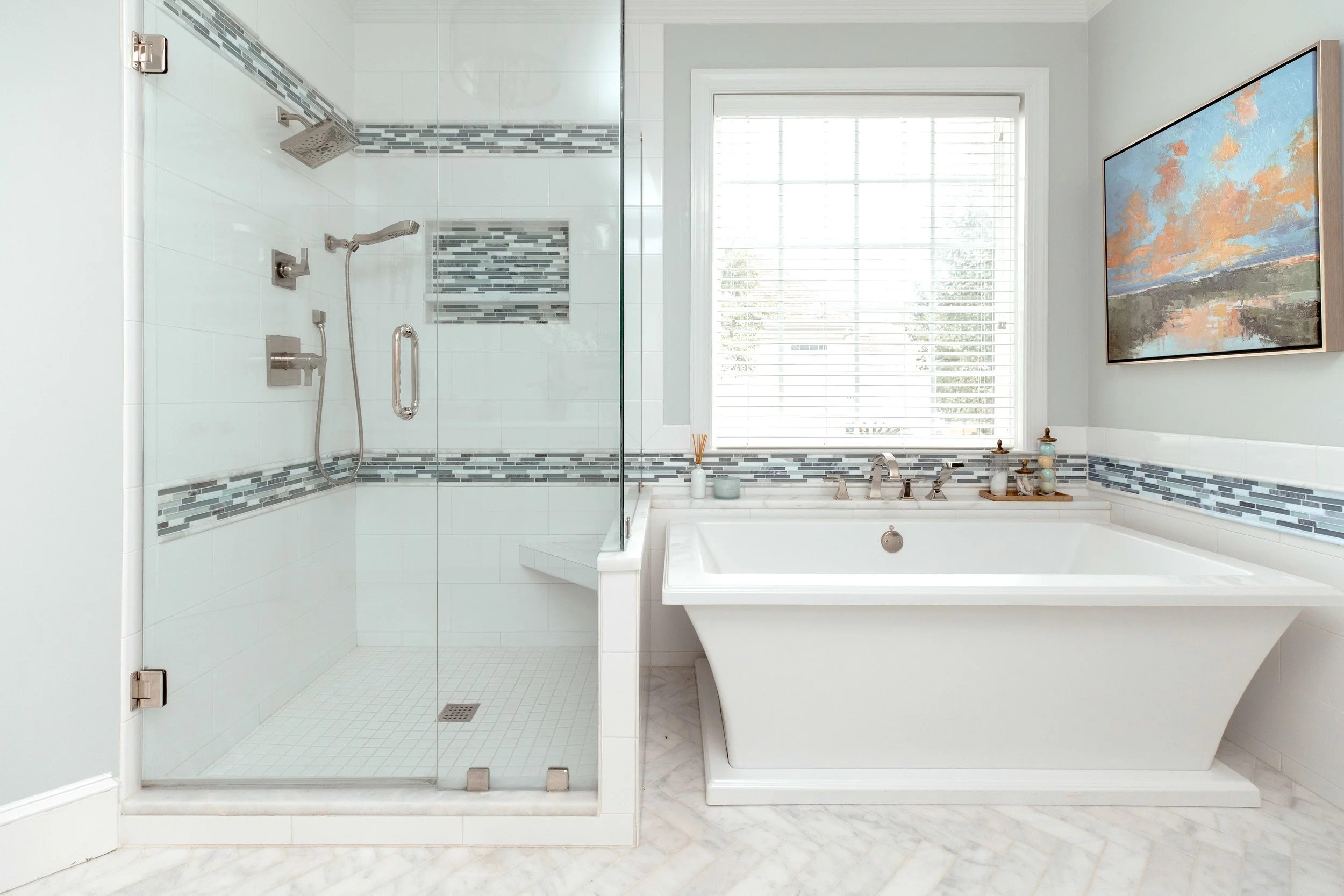 A spa-inspired master bathroom by Cossart Design, featuring custom herringbone floors, white and blue accents, a soaking tub, shower with custom tile, and luxurious gold fixtures. Designed for serenity, function, and elevated style, this space is a p