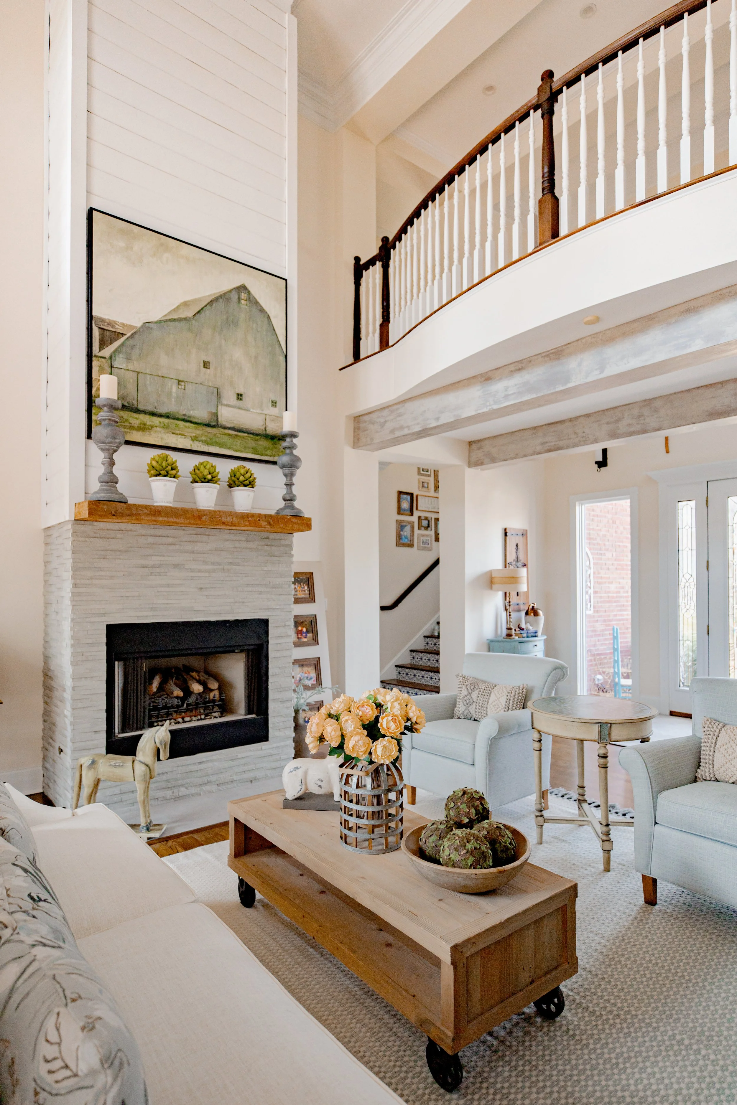 A sophisticated formal living room designed by Cossart Design, anchored by a dramatic floor-to-ceiling fireplace and custom furnishings that combine style and comfort. The space is layered with textures, tailored seating, and carefully chosen accent 