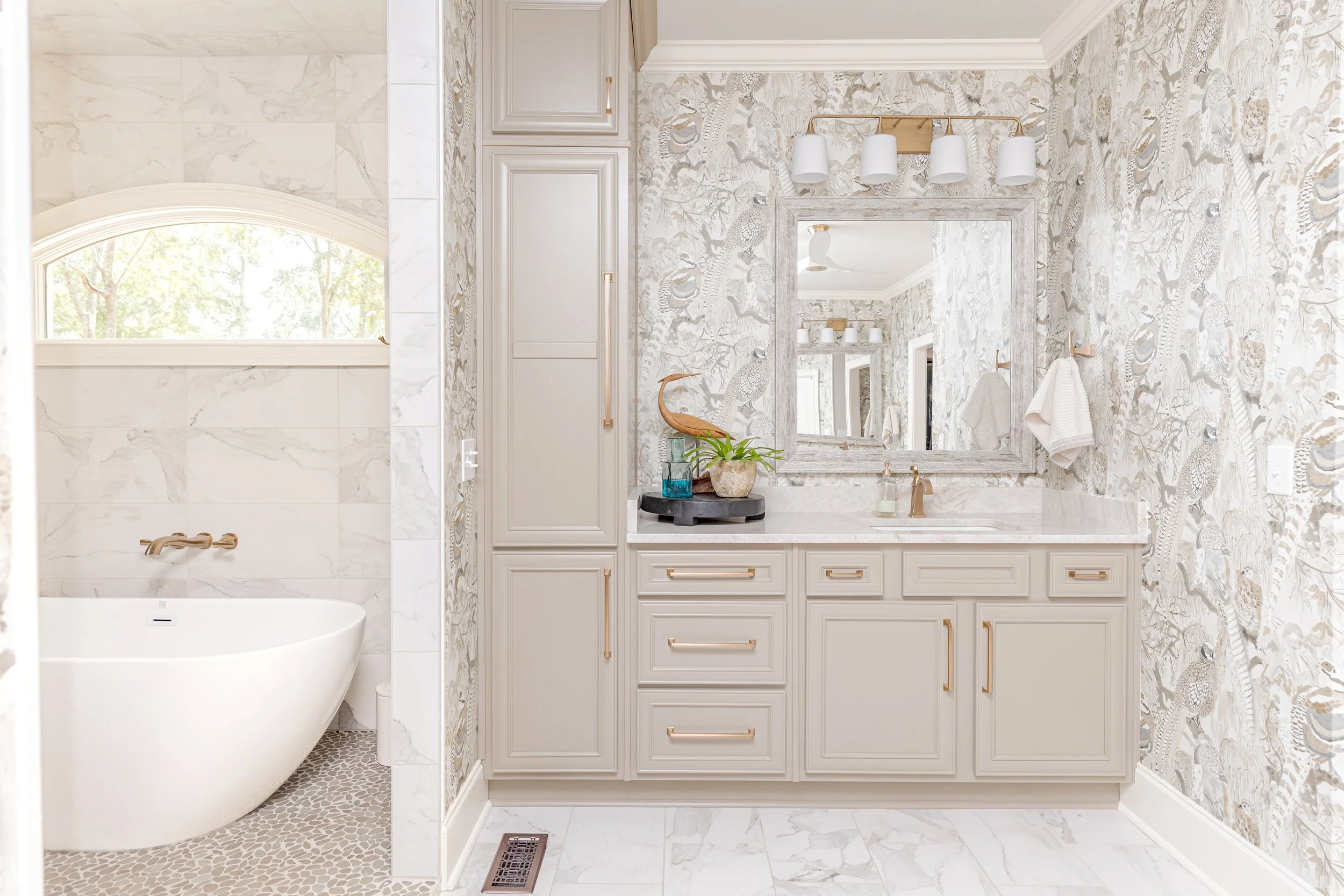 A spa-inspired primary bathroom designed for relaxation and daily ritual. Elevated materials, balanced lighting, and thoughtful layouts create a space that feels calming, timeless, and refined. The textured wallpaper custom tile, and gold finishes br