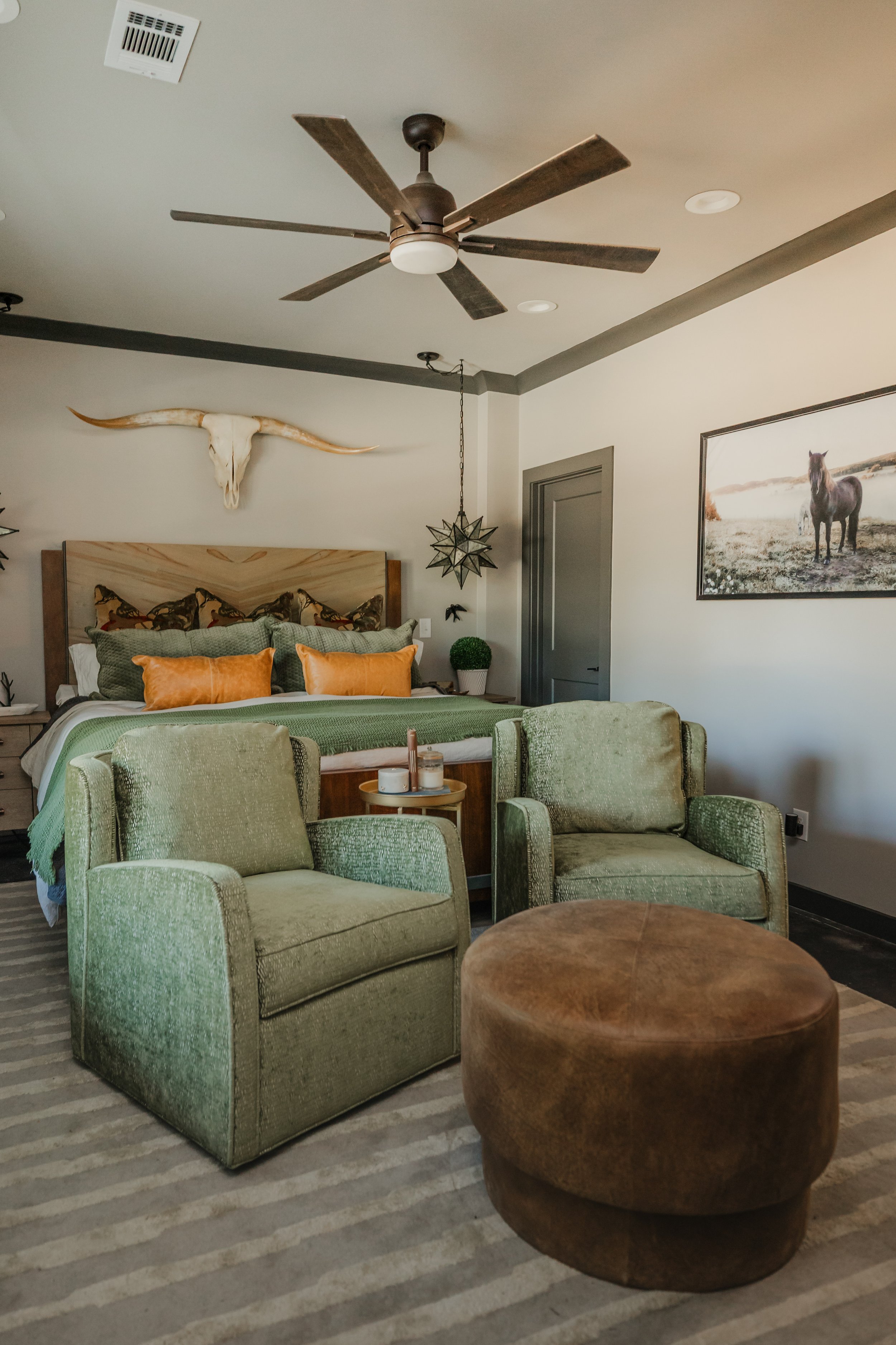 A luxurious master bedroom retreat designed by Cossart Design, featuring custom pillows and carefully layered textiles that add warmth and personality to this masculine lodge‑style home. Soft green hues and refined finishes create a calming yet sophi