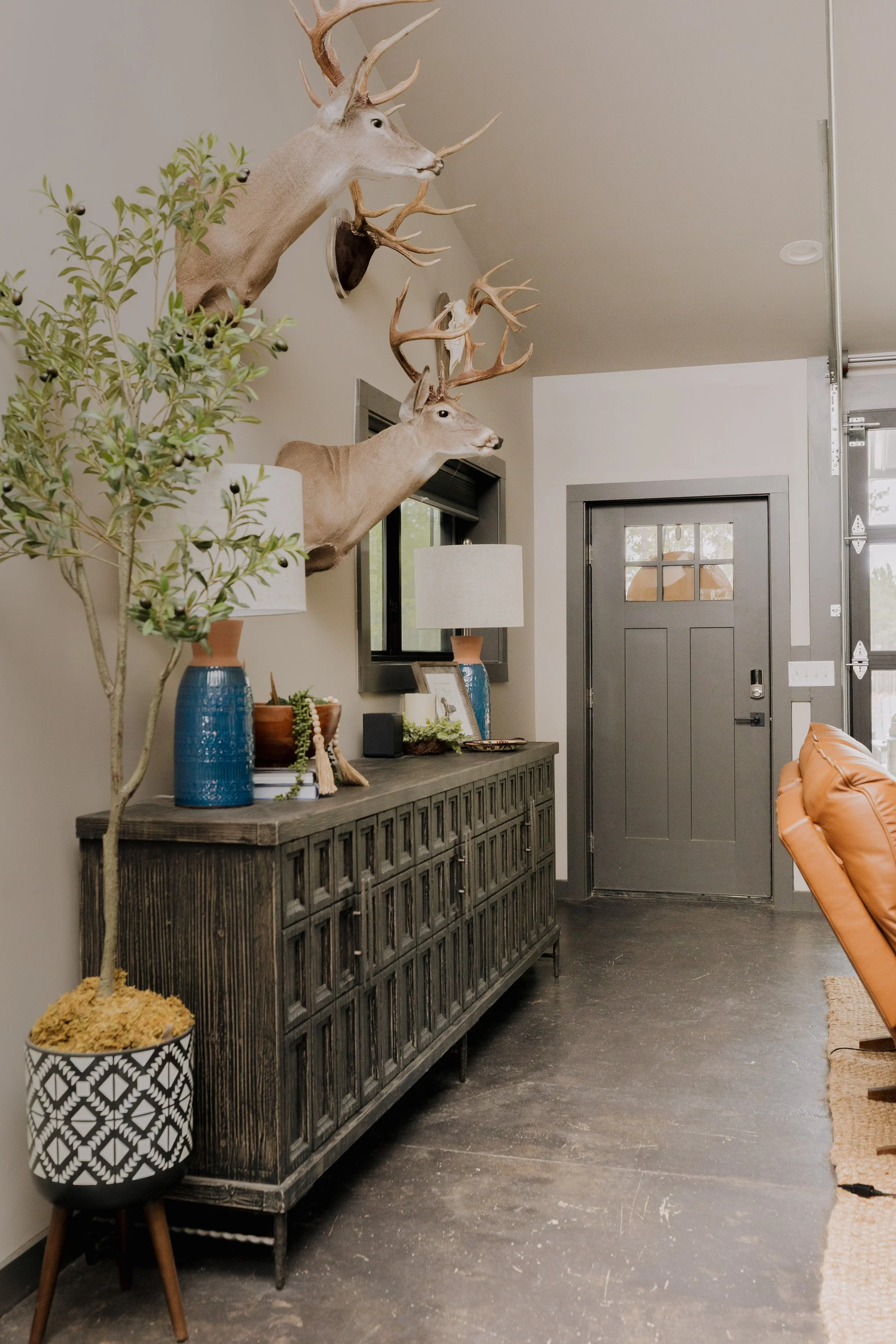 A striking entryway by Cossart Design in this Hawkinsville, GA barndominium that masterfully blends industrial accents with masculine design. Rich green and wood tones, along with tailored furnishings create a lodge‑inspired environment that feels bo