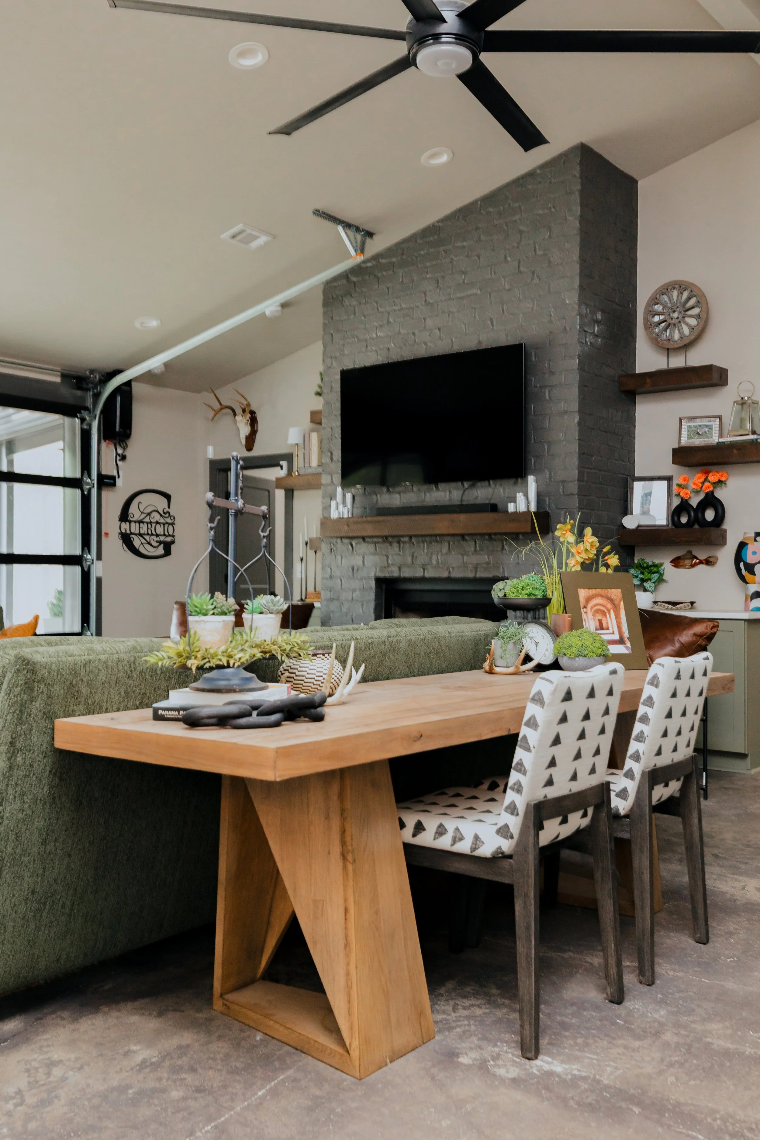 A striking open concept living space by Cossart Design in this Hawkinsville, GA barndominium that masterfully blends industrial accents with masculine design. Rich green and wood tones, along with modern tailored furnishings create a lodge‑inspired e