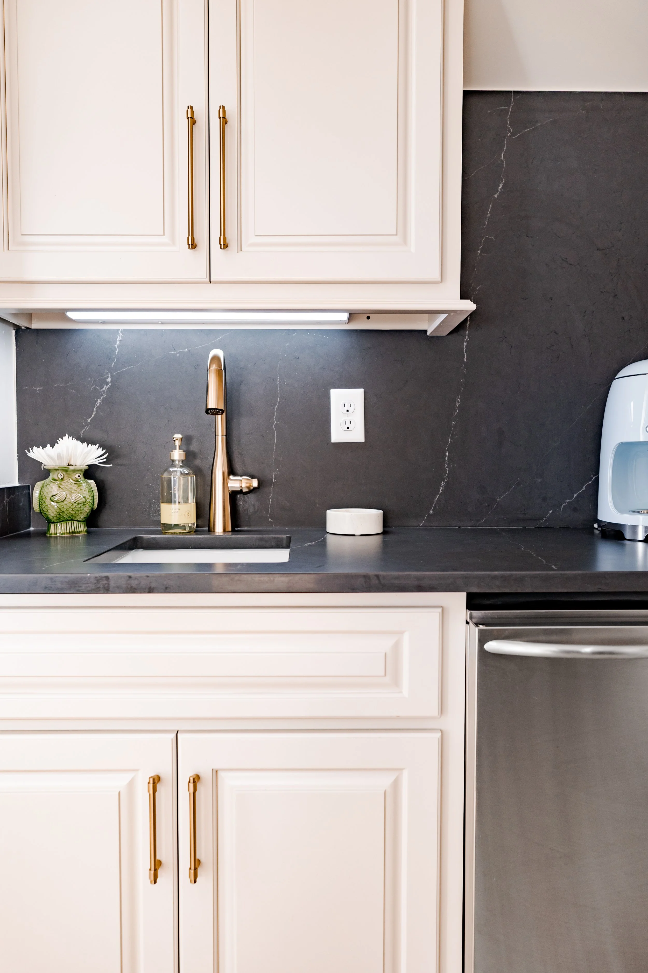 A custom wet bar designed to elevate both entertaining and everyday living. Tailored cabinetry is paired with custom black marble countertops with gold finished hardware adding a layer of timeless elegance and natural beauty. Thoughtful storage, refi