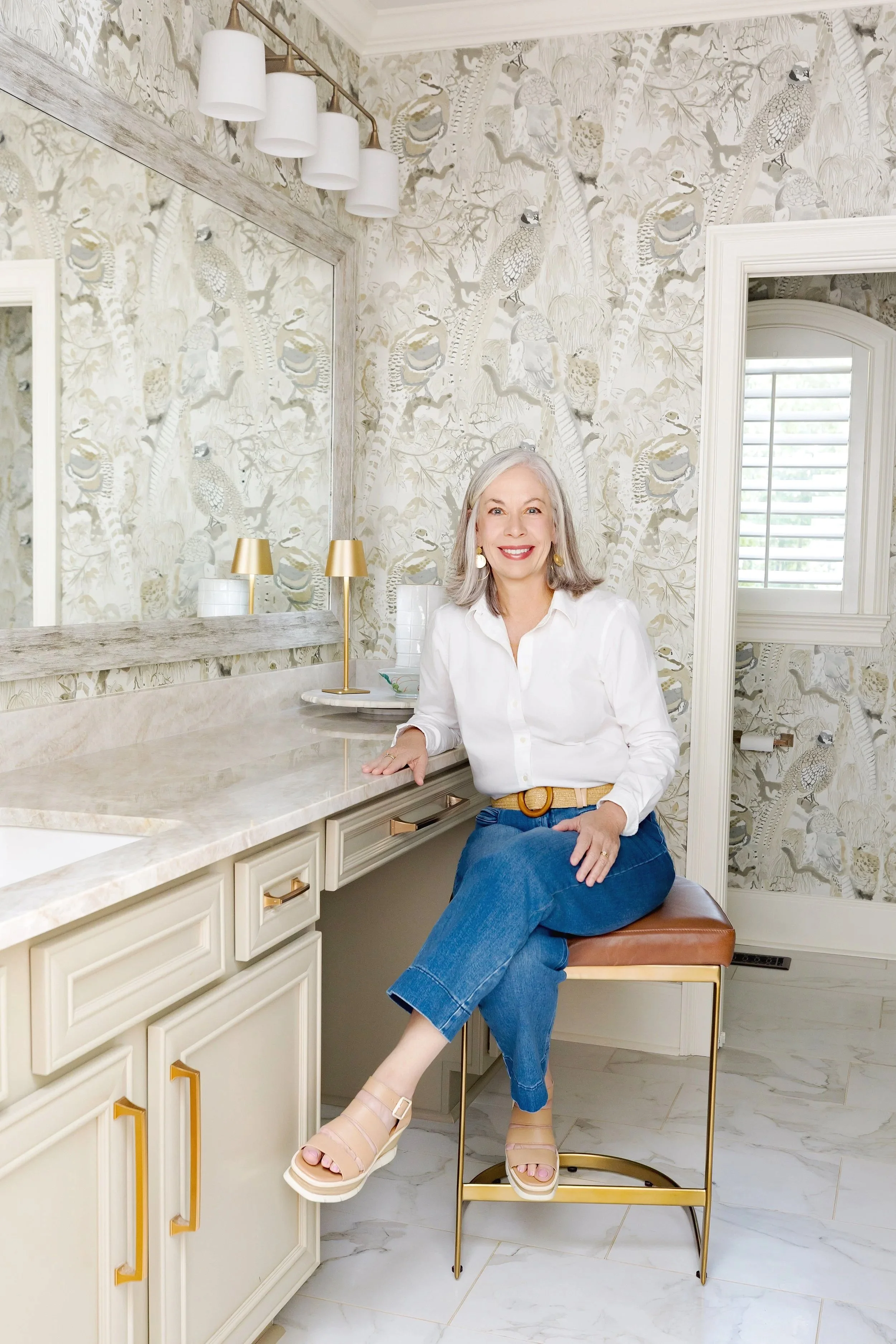 Trish Cossart of Cossart Design in Perry, GA, seated in a cozy luxury master bathroom she designed with custom finishes and Southern style.