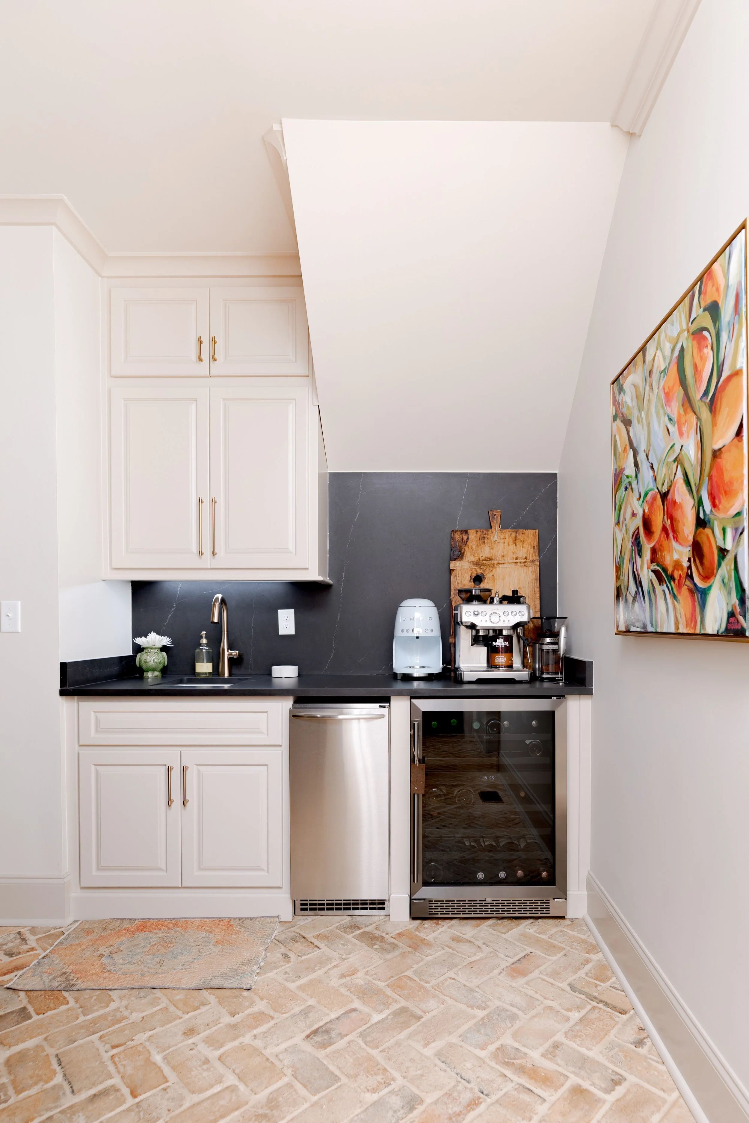 A custom wet bar designed to elevate both entertaining and everyday living. Tailored cabinetry is paired with custom black marble countertops with gold finished hardware adding a layer of timeless elegance and natural beauty. Thoughtful storage, wine