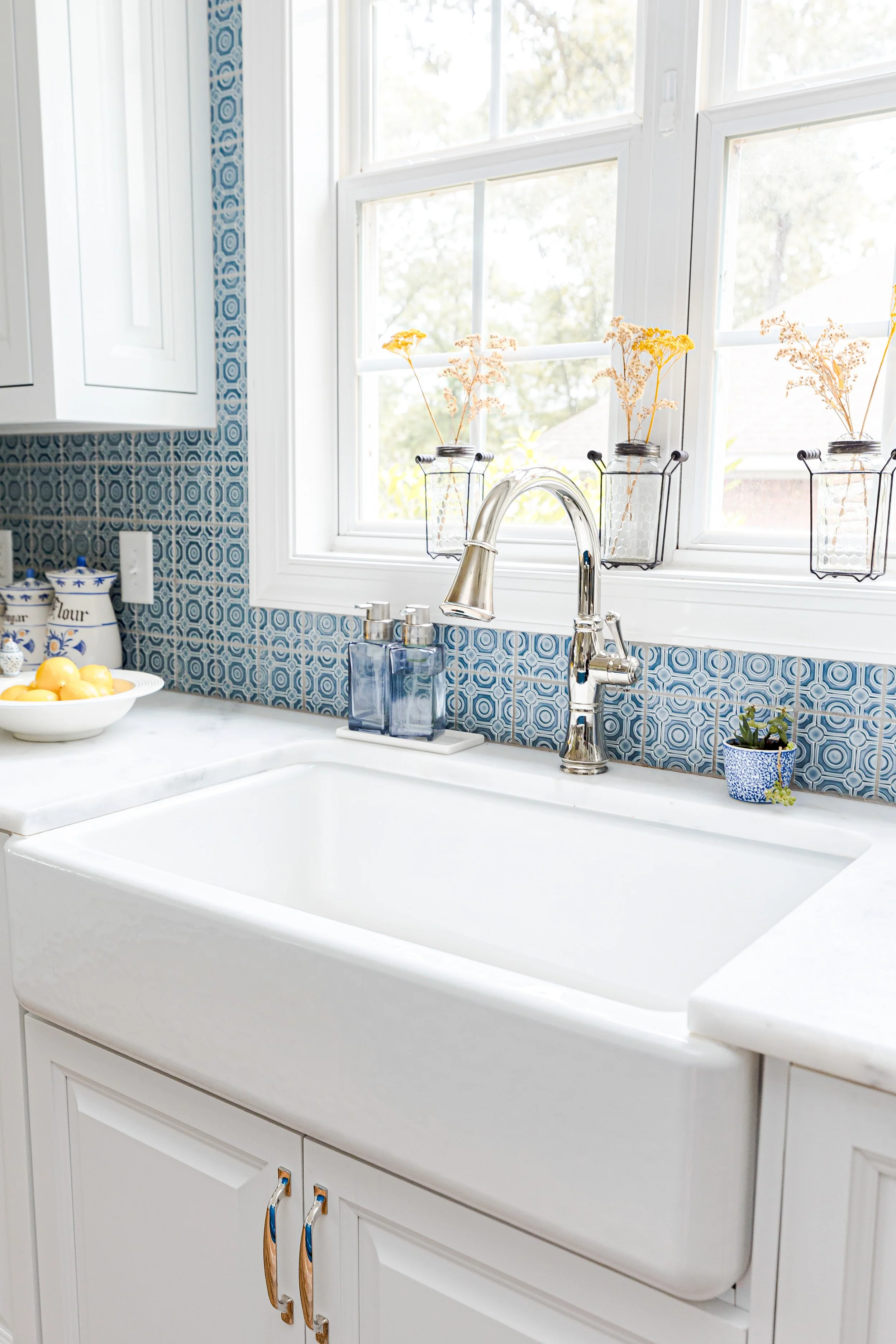 A bright, functional, and stylish kitchen designed by Cossart Design, featuring crisp white cabinetry, custom backsplash, and playful blue accents. Thoughtfully selected finishes and layout make this kitchen ideal for cooking, entertaining, and daily