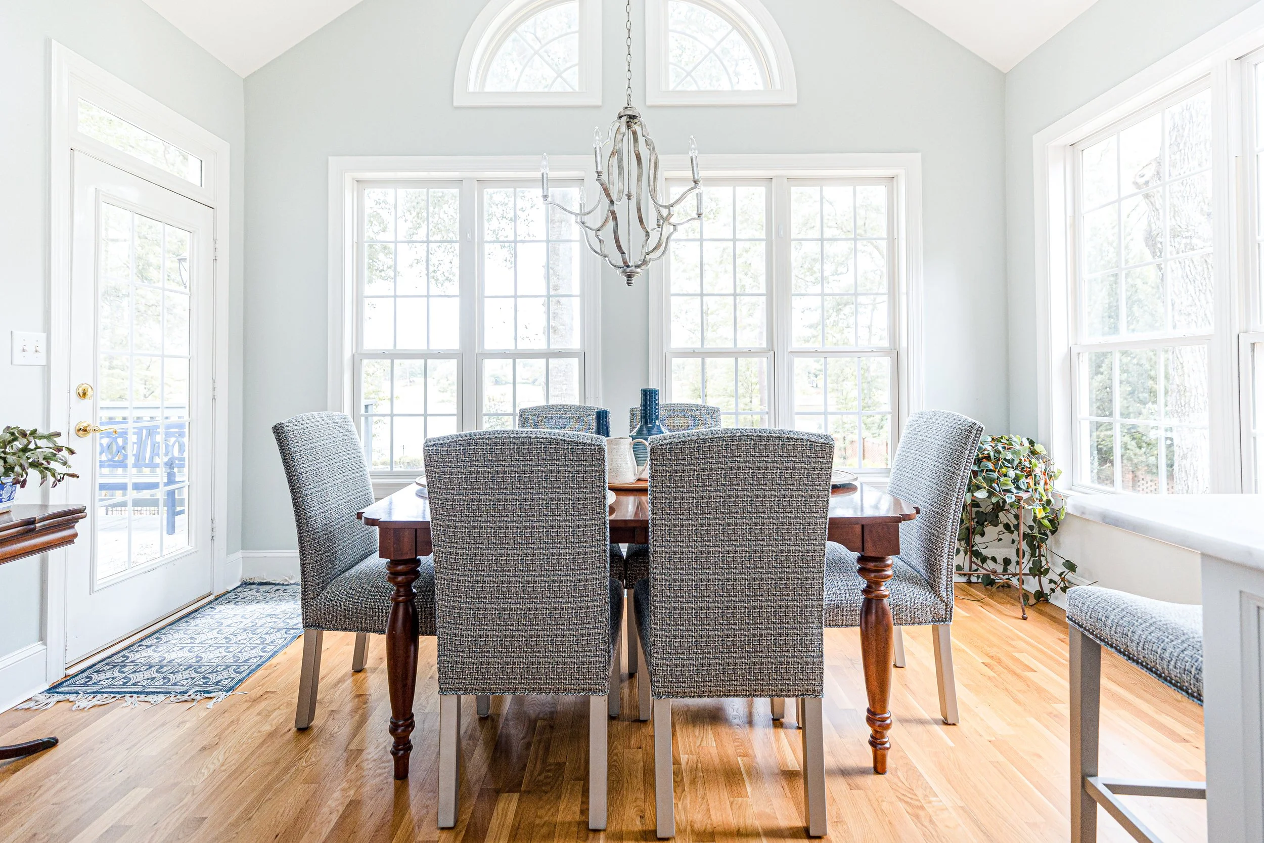 A sunlit eat-in dining area by Cossart Design, featuring expansive windows, elegant furnishings, and thoughtful details that create a bright, inviting space for meals and gatherings. The design balances Southern charm with elevated style, perfect for