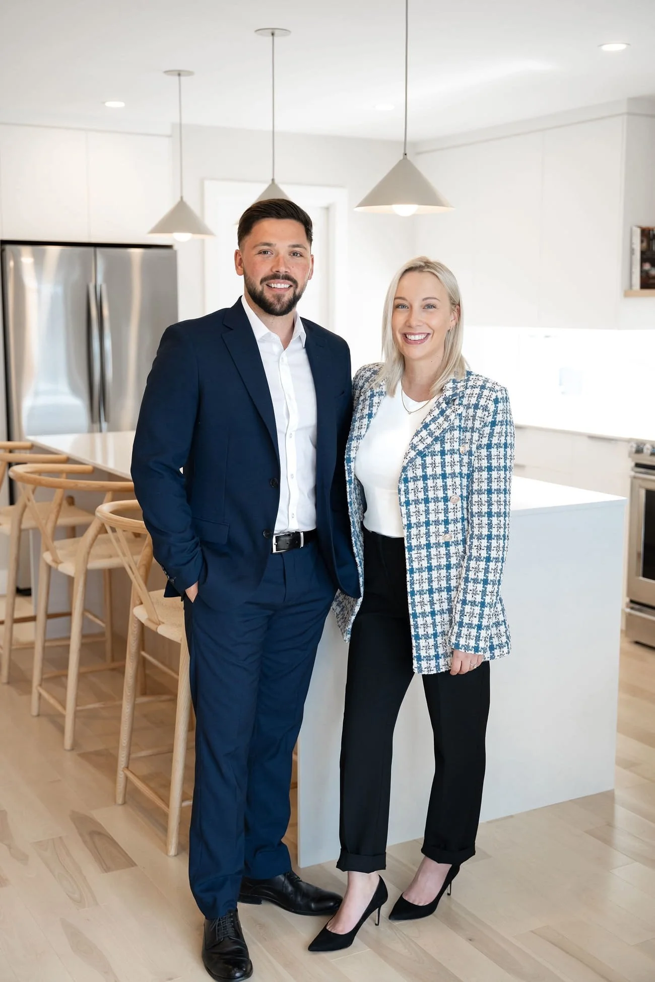 Un homme et une femme en vêtements d'affaires sourient dans une cuisine moderne