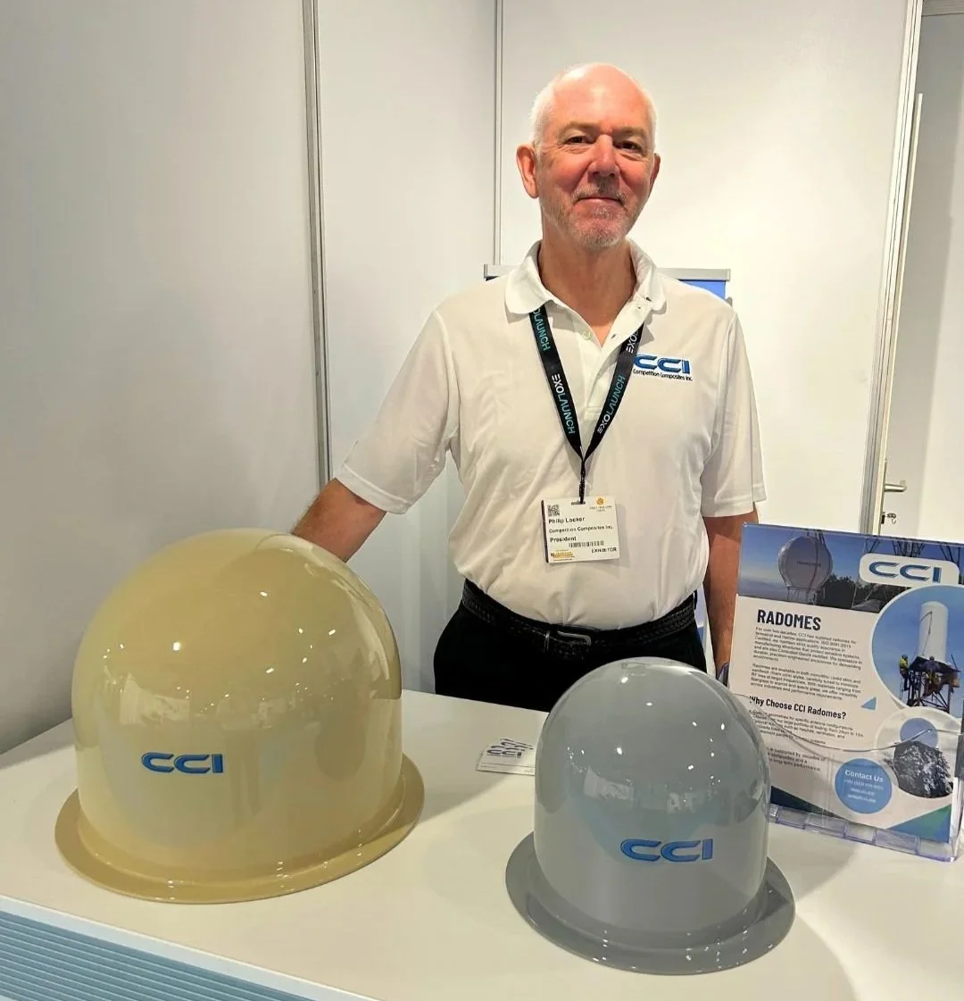 CCI founder with two radomes shown at trade show booth
