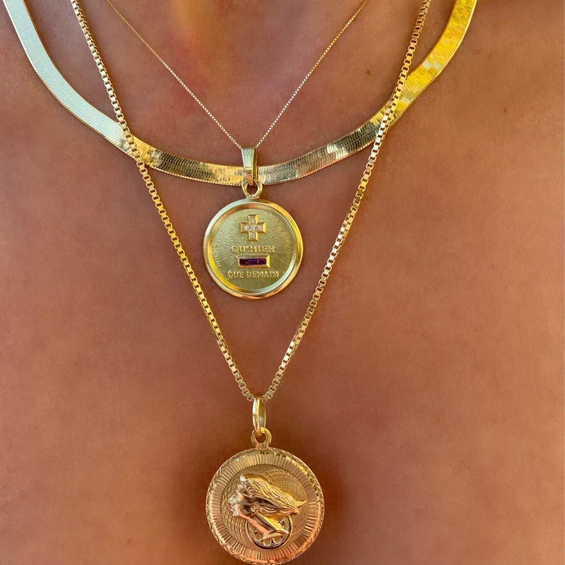 Gadgets en or autour du cou, comprenant deux colliers avec pendentifs, one avec un symbole médical et l'autre avec un cheval de course.