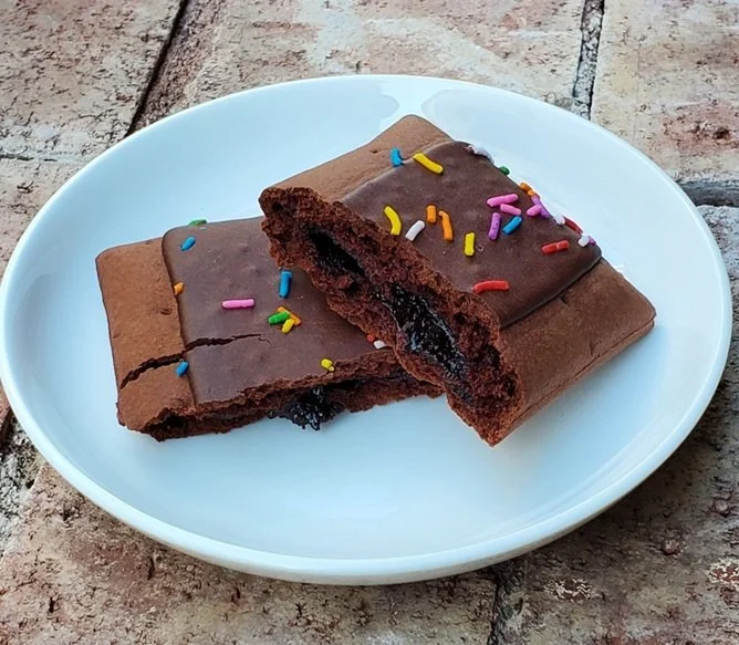 Legendary Chocolate Cake flavored protein pastry topped with colorful sprinkles on a white plate,
