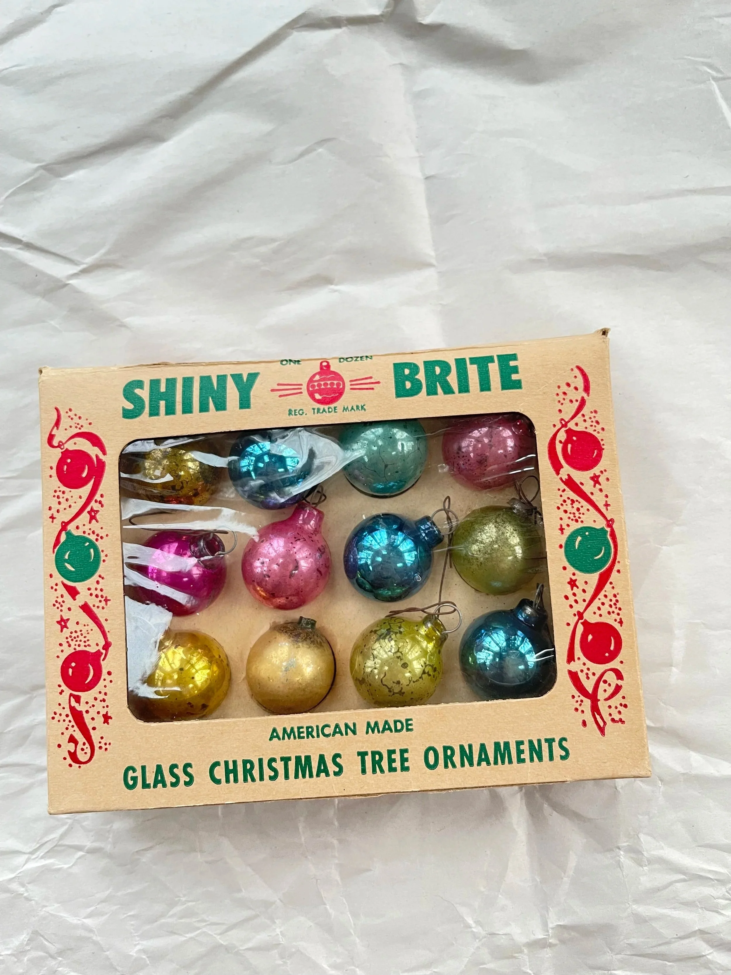 Twelve feather-size vintage Shiny Brite glass ornaments in their original box.