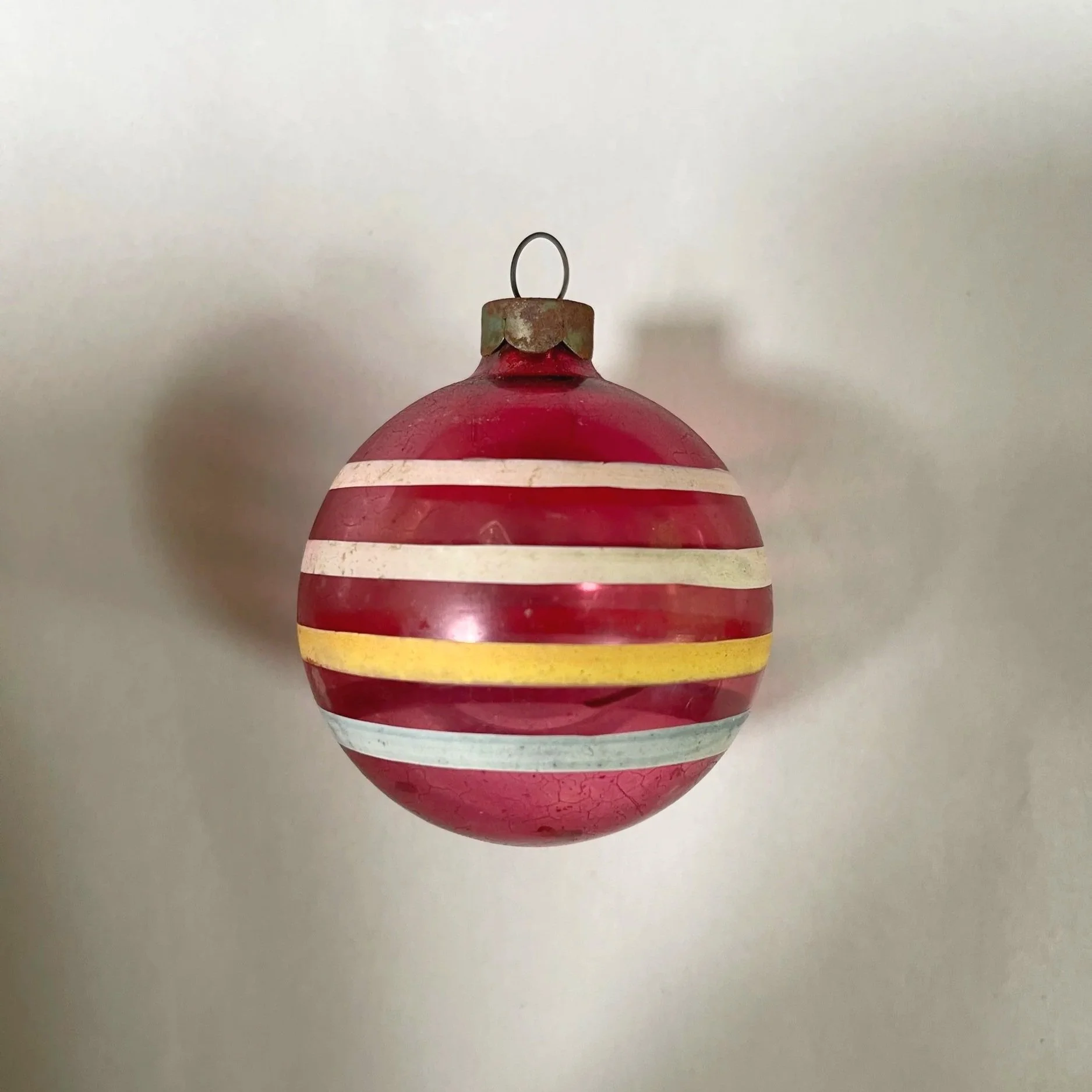 Vintage unsilvered glass Christmas ornament with red stripes and tinsel inside.