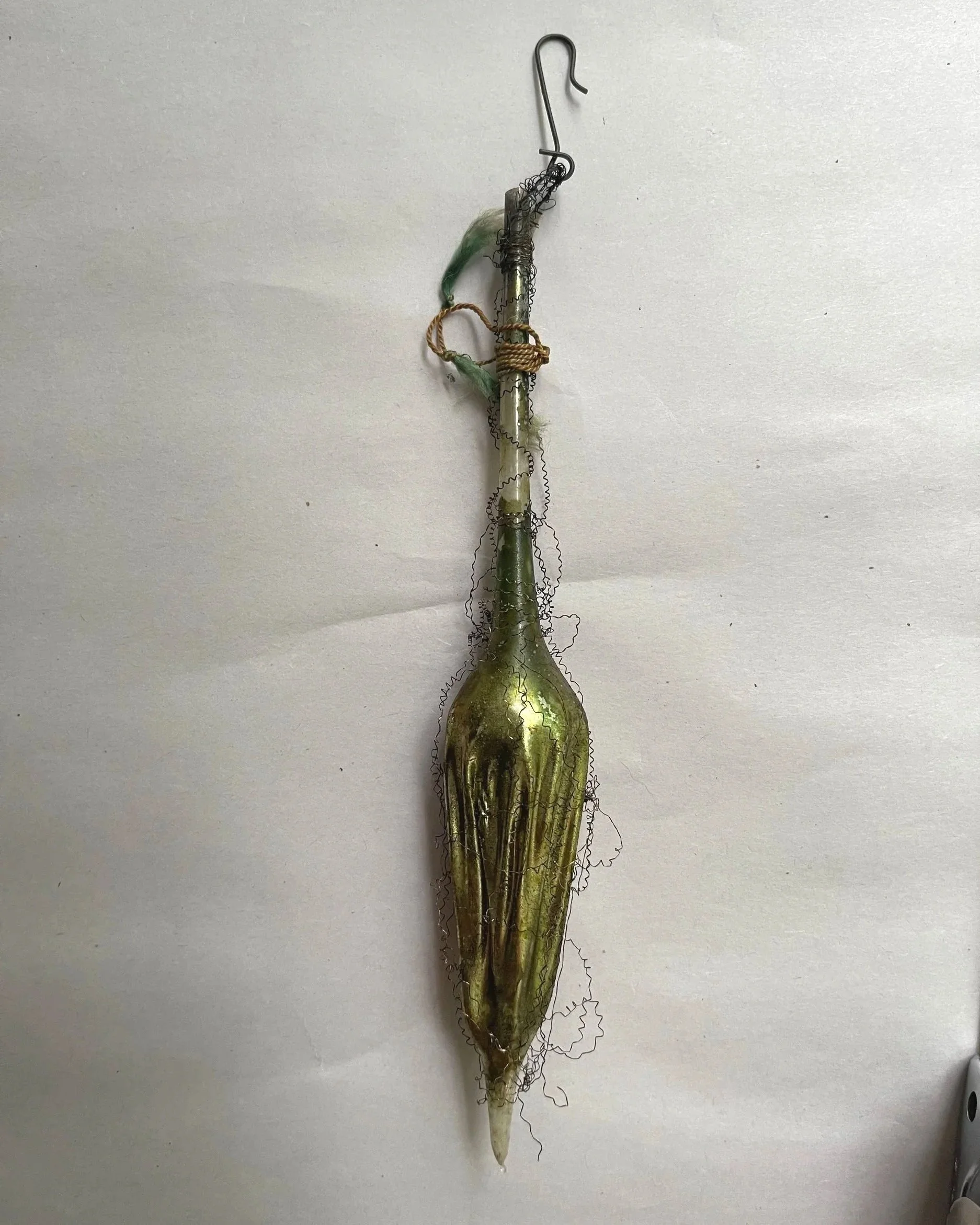 Large antique German glass parasol ornament with a green-gold body, curved wire handle, and wire wrapping.