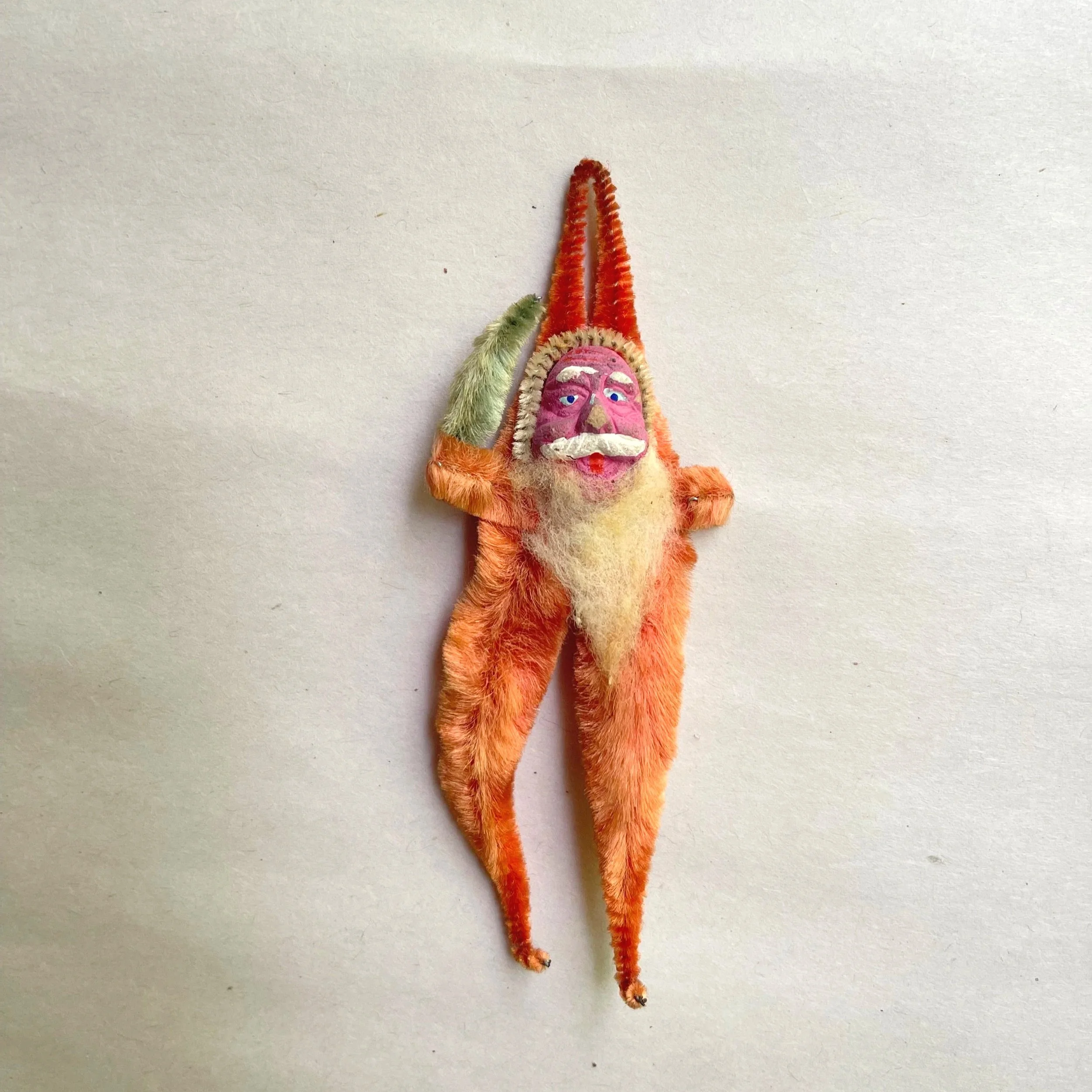 Vintage chenille Santa ornament with an orange suit, pointed hat, painted composition face, and long legs.