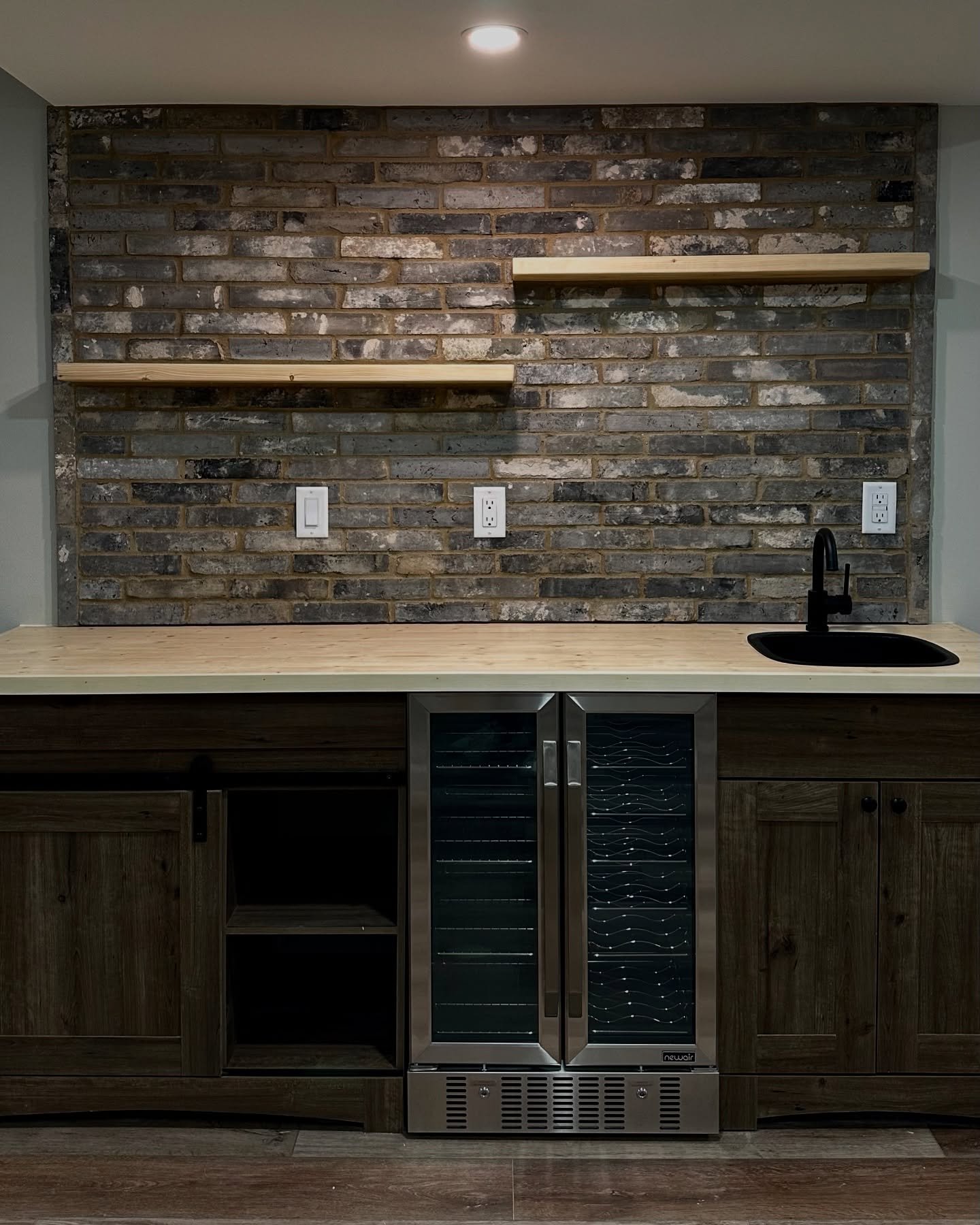 This custom wet bar became the centerpiece of our latest basement remodel! The reclaimed brick perfectly ties into the natural wood countertop and floating shelves for a cozy rustic feel.