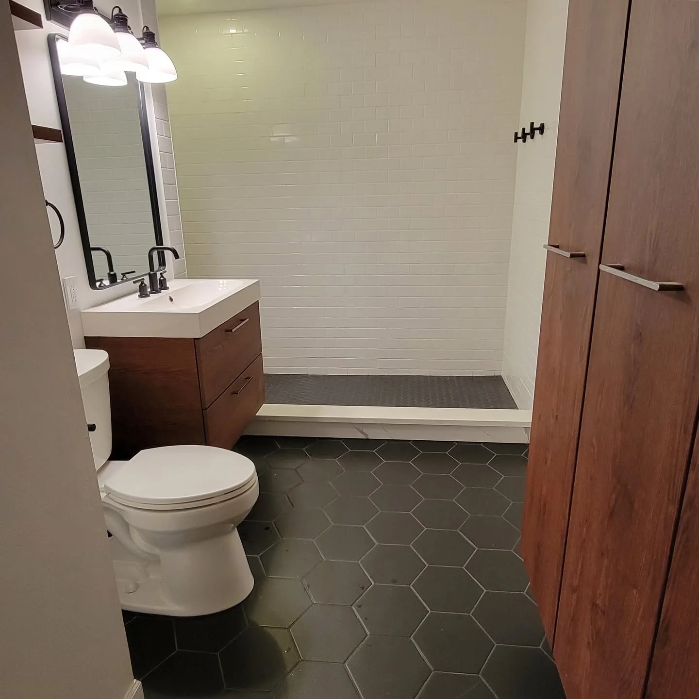 Sharing another recent bathroom remodel! Large black hexagon floor tiles blend seamlessly within scaled down matching tile in the shower. 

All that&rsquo;s missing is the shower door! 

Reach out today for a free estimate on your next project. 

262